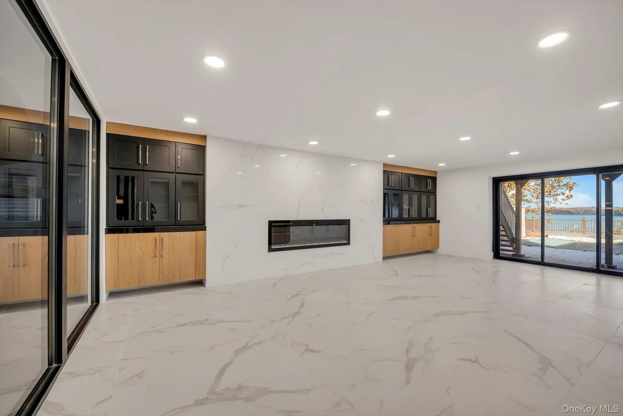 Unfurnished living room featuring light marble finish floors and recessed lighting Unfurnished living room featuring light marble finish floors and recessed lighting
