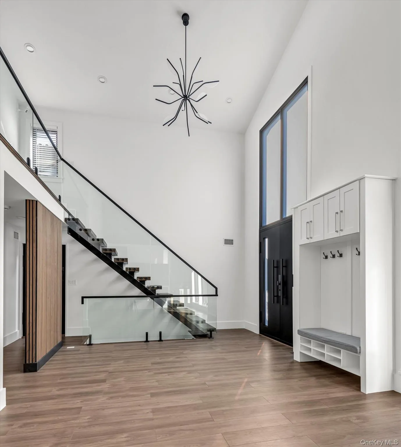 Entryway with plenty of natural light, a towering ceiling, a chandelier, light wood finished floors, and stairs Entryway with plenty of natural light, a towering ceiling, a chandelier, light wood finished floors, and stairs