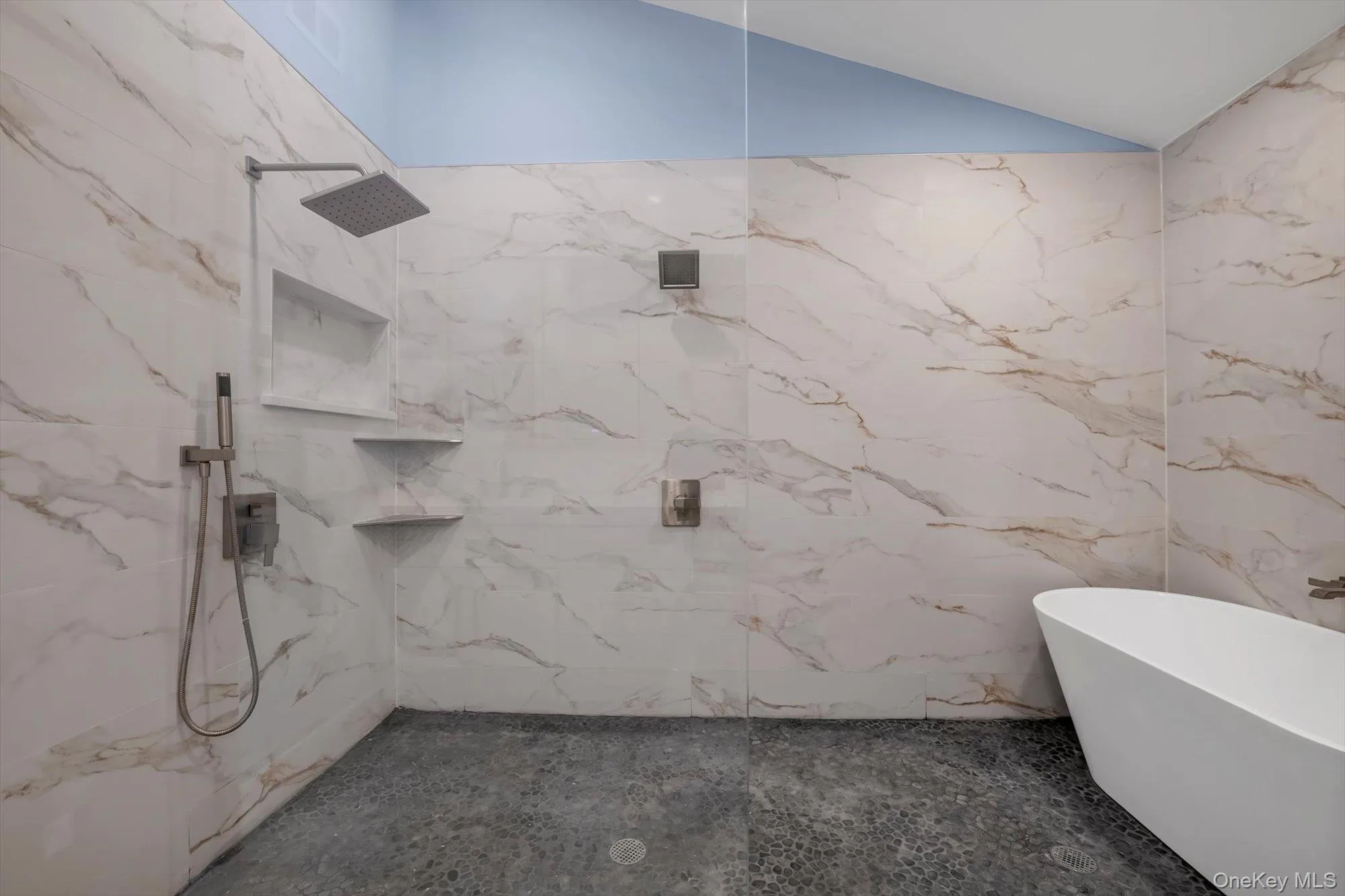 Bathroom featuring a freestanding bath, lofted ceiling, and a marble finish shower Bathroom featuring a freestanding bath, lofted ceiling, and a marble finish shower