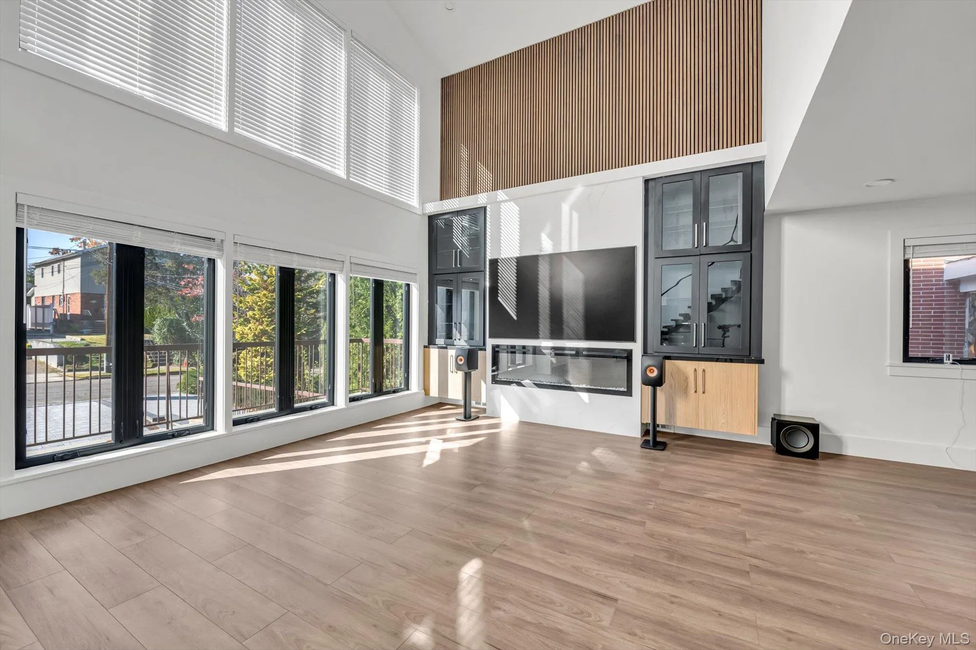 Unfurnished living room featuring a high ceiling and light wood-style floors Unfurnished living room featuring a high ceiling and light wood-style floors