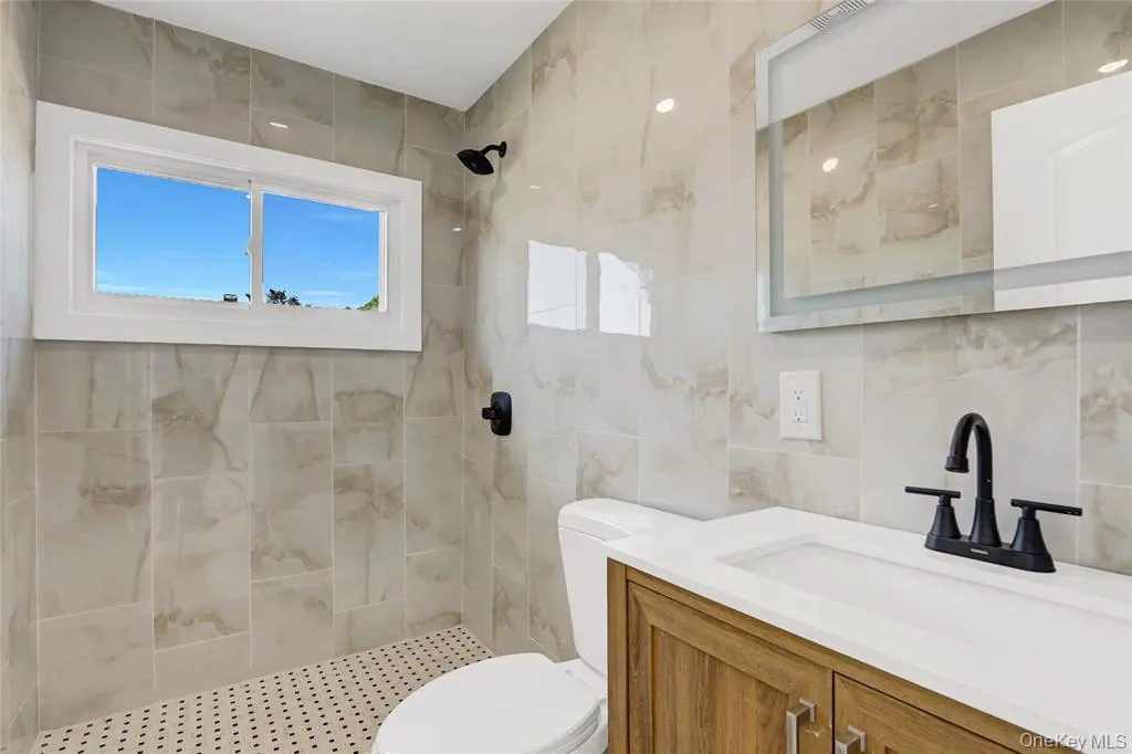 Bathroom with vanity, tile walls, and a tile shower Bathroom with vanity, tile walls, and a tile shower