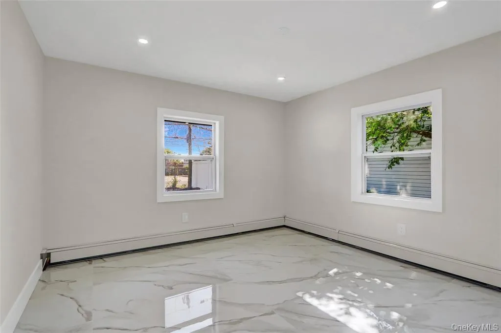 Unfurnished room with light marble finish floors, plenty of natural light, recessed lighting, and a baseboard heating unit Unfurnished room with light marble finish floors, plenty of natural light, recessed lighting, and a baseboard heating unit