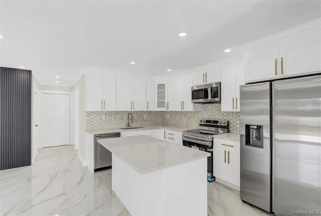 Kitchen with stainless steel appliances, light marble finish flooring, light stone counters, white cabinets, and recessed lighting Kitchen with stainless steel appliances, light marble finish flooring, light stone counters, white cabinets, and recessed lighting