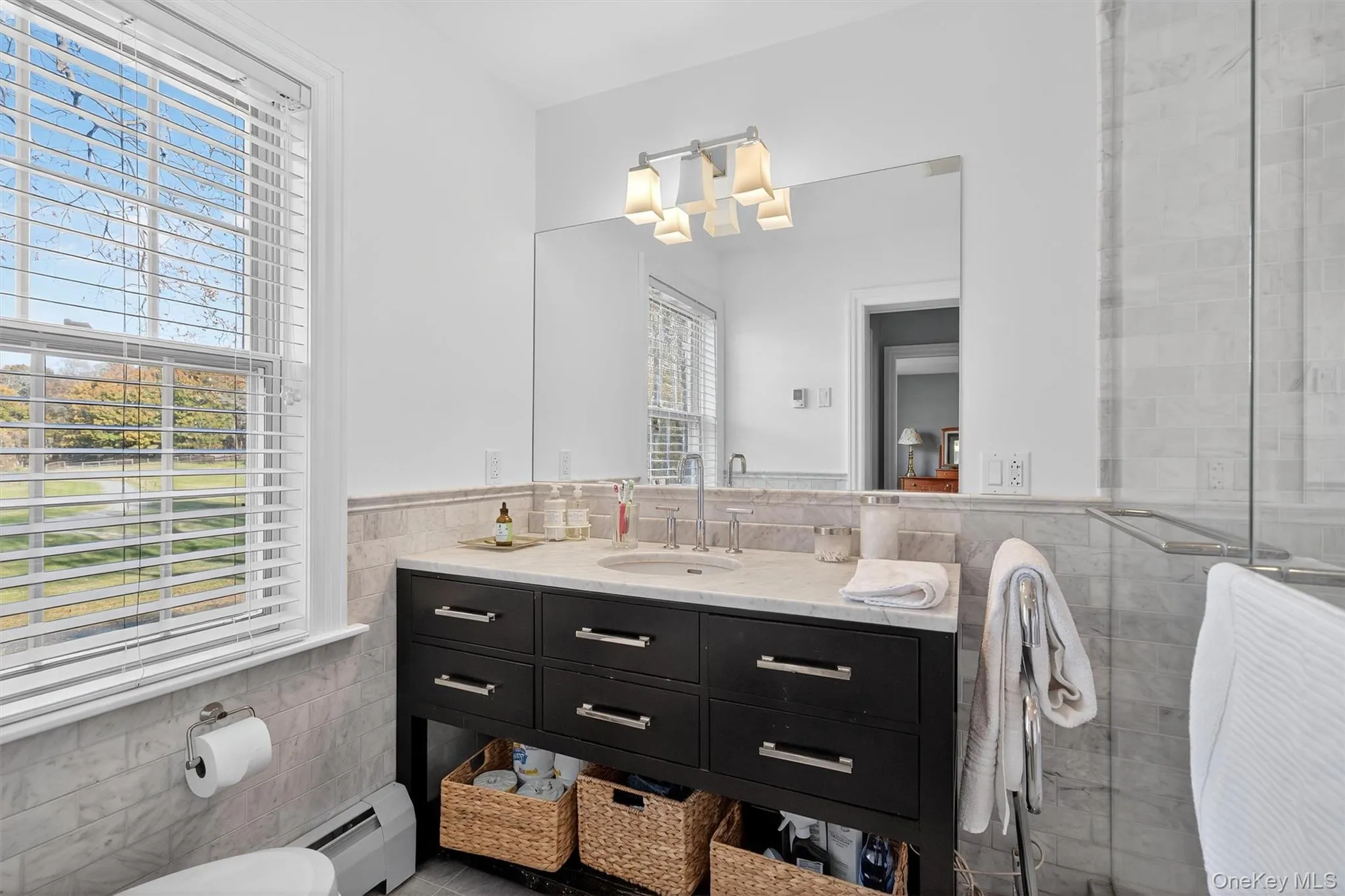 Bathroom with tile walls, vanity, a baseboard heating unit, a wainscoted wall, and a stall shower Bathroom with tile walls, vanity, a baseboard heating unit, a wainscoted wall, and a stall shower