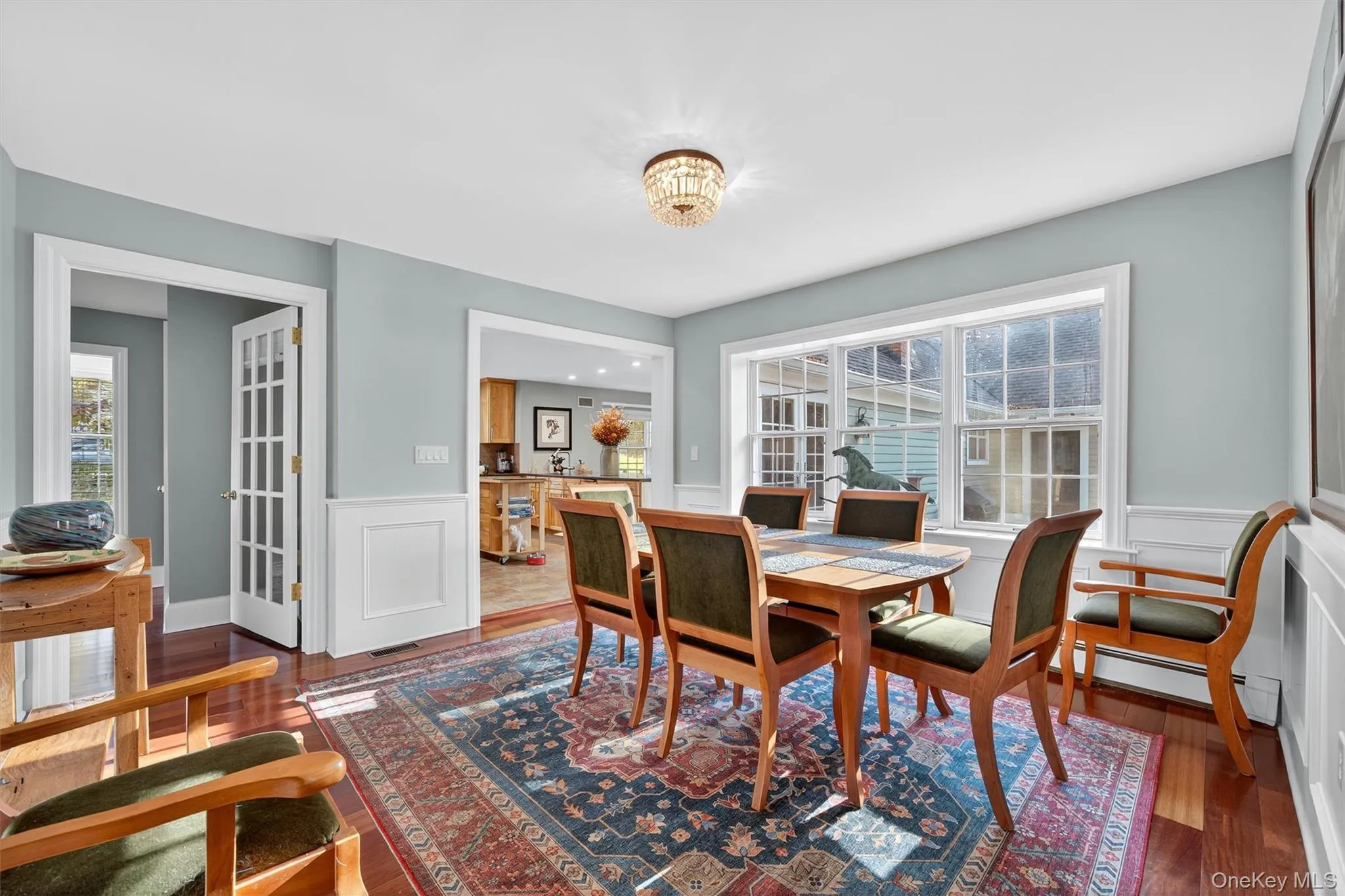 Dining space with wainscoting, dark wood finished floors, and a decorative wall Dining space with wainscoting, dark wood finished floors, and a decorative wall