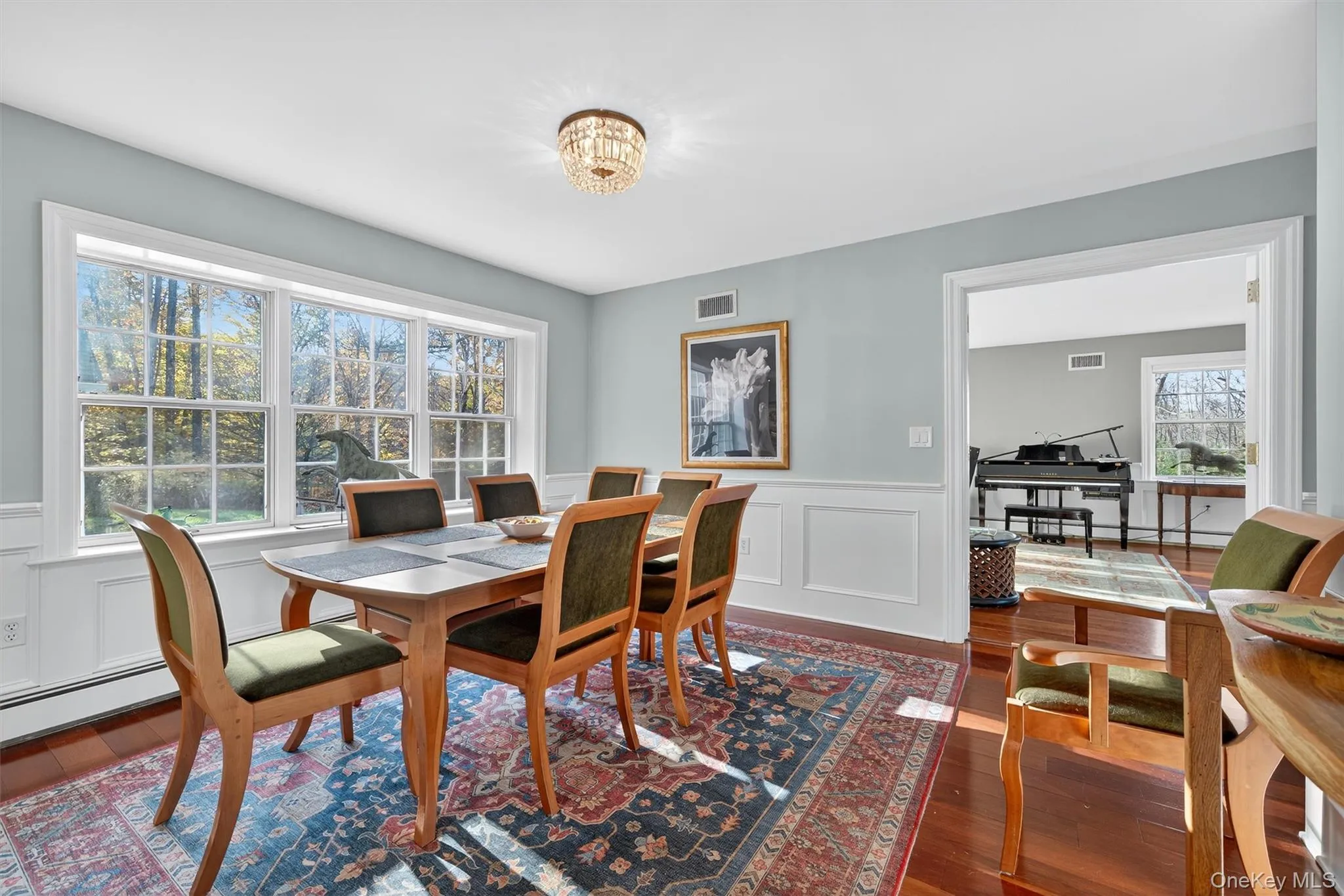 Dining room featuring a decorative wall, wainscoting, and dark wood-type flooring Dining room featuring a decorative wall, wainscoting, and dark wood-type flooring