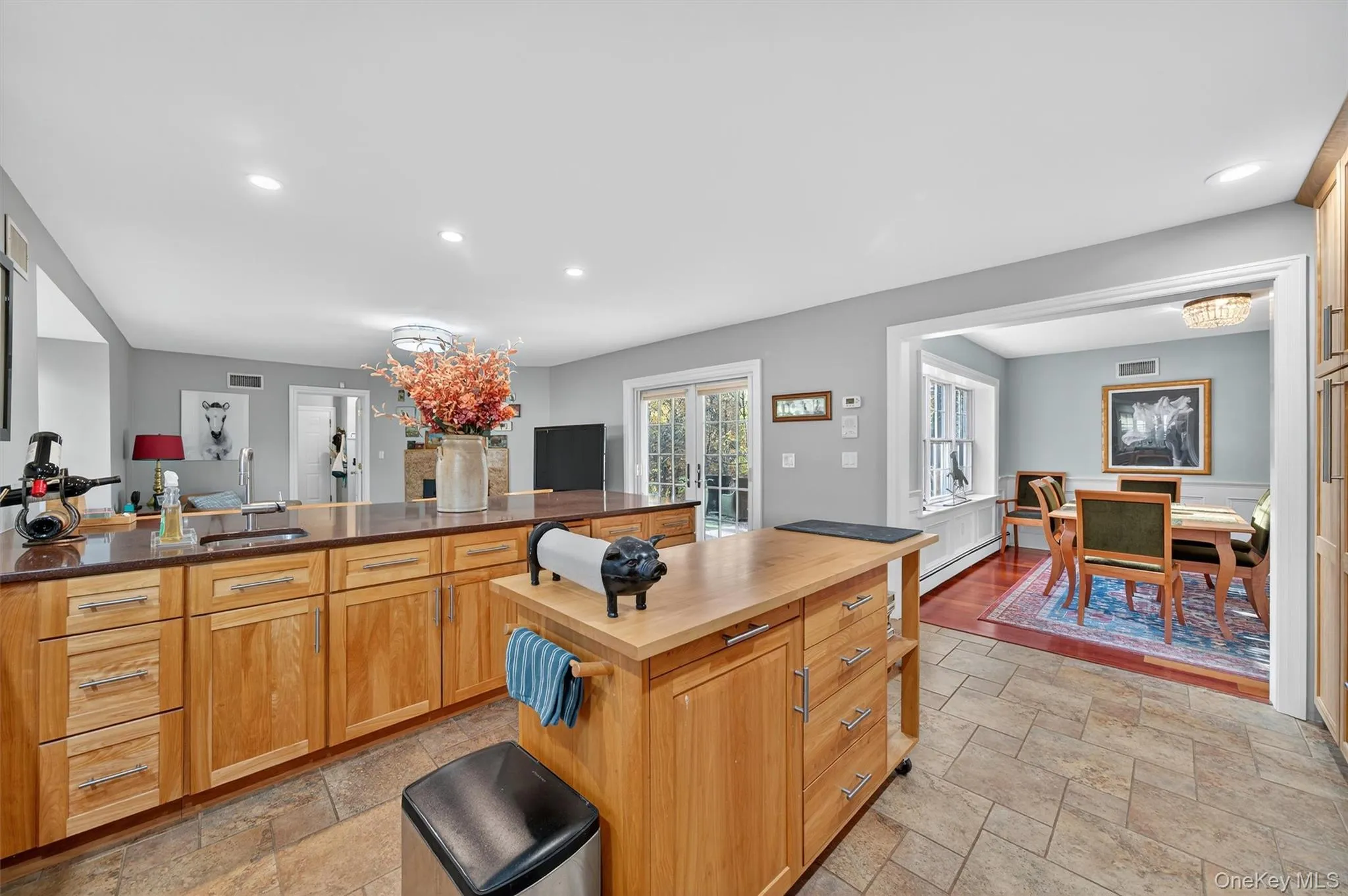Kitchen featuring recessed lighting, brown cabinets, a baseboard heating unit, stone tile flooring, and butcher block countertops Kitchen featuring recessed lighting, brown cabinets, a baseboard heating unit, stone tile flooring, and butcher block countertops