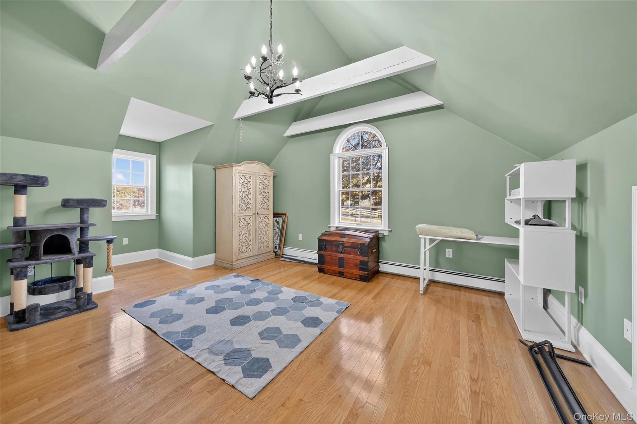 Additional living space with healthy amount of natural light, vaulted ceiling, light wood-style floors, a chandelier, and a baseboard heating unit Additional living space with healthy amount of natural light, vaulted ceiling, light wood-style floors, a chandelier, and a baseboard heating unit