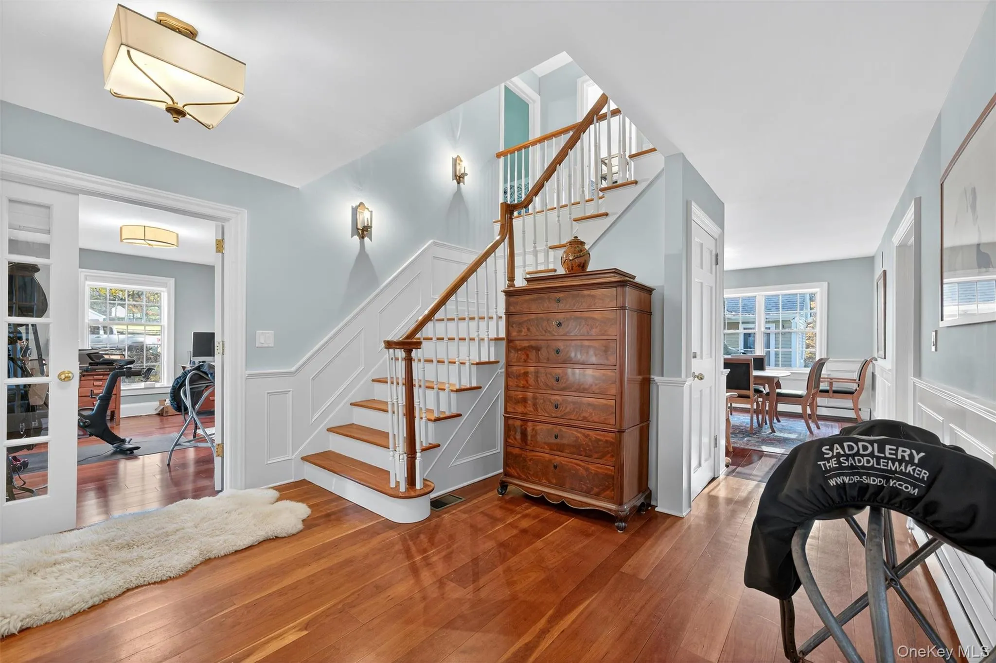 Stairway featuring wainscoting, a decorative wall, and wood-type flooring Stairway featuring wainscoting, a decorative wall, and wood-type flooring