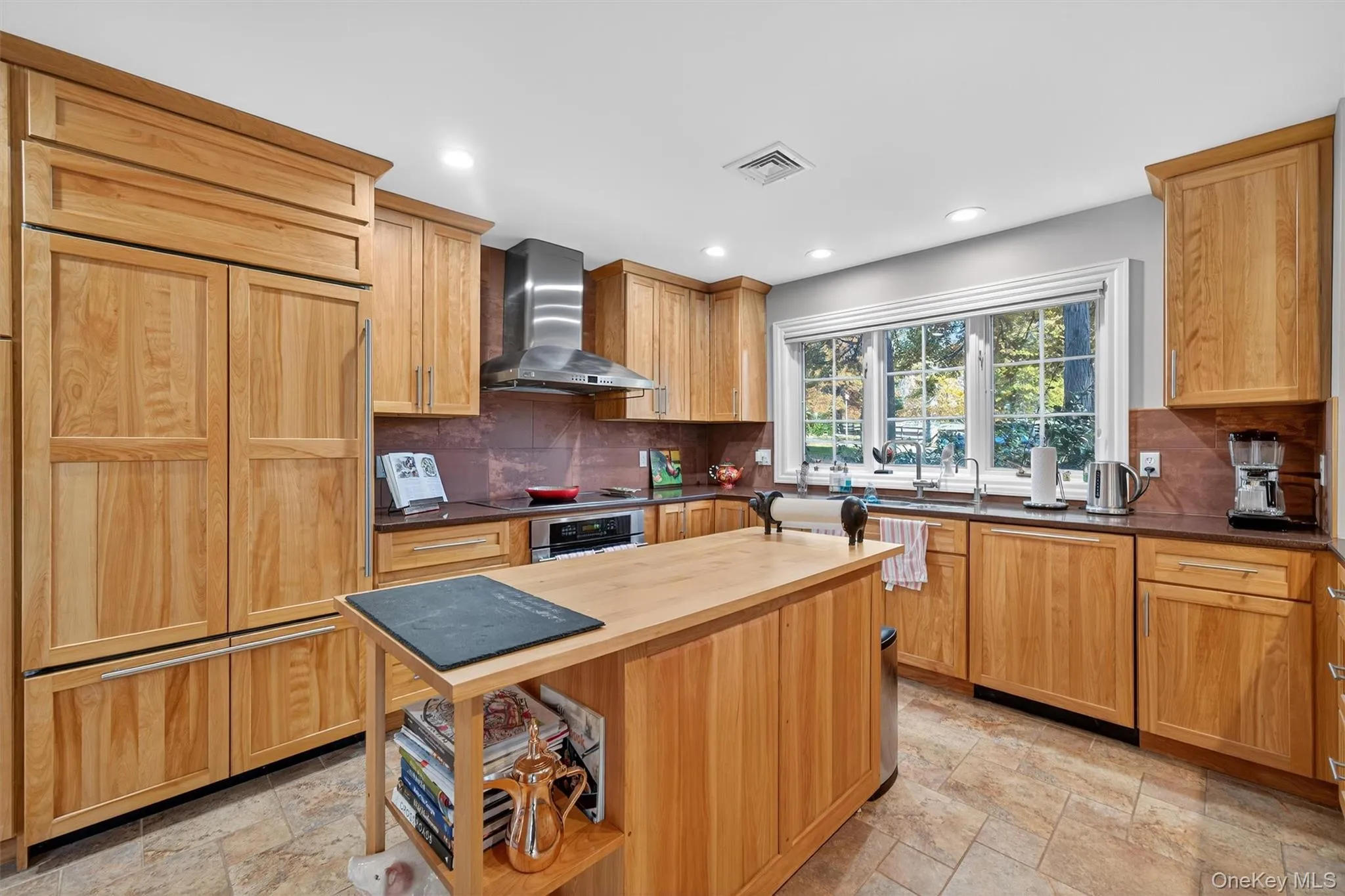 Kitchen featuring stone tile floors, wall chimney range hood, dishwasher, oven, and recessed lighting Kitchen featuring stone tile floors, wall chimney range hood, dishwasher, oven, and recessed lighting