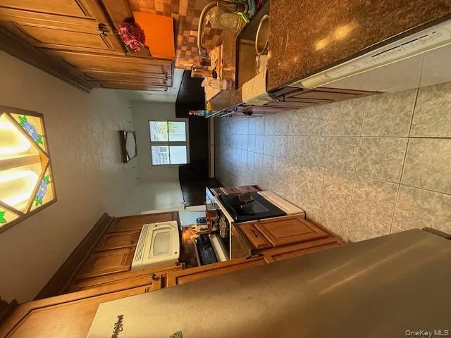 Kitchen with fridge, white stove, a wainscoted wall, dark stone countertops, and backsplash Kitchen with fridge, white stove, a wainscoted wall, dark stone countertops, and backsplash