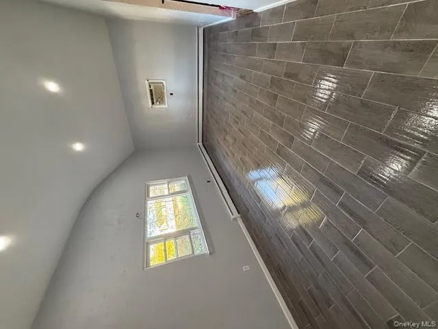 Empty room featuring lofted ceiling, wood finish floors, recessed lighting, a baseboard heating unit, and an AC wall unit Empty room featuring lofted ceiling, wood finish floors, recessed lighting, a baseboard heating unit, and an AC wall unit