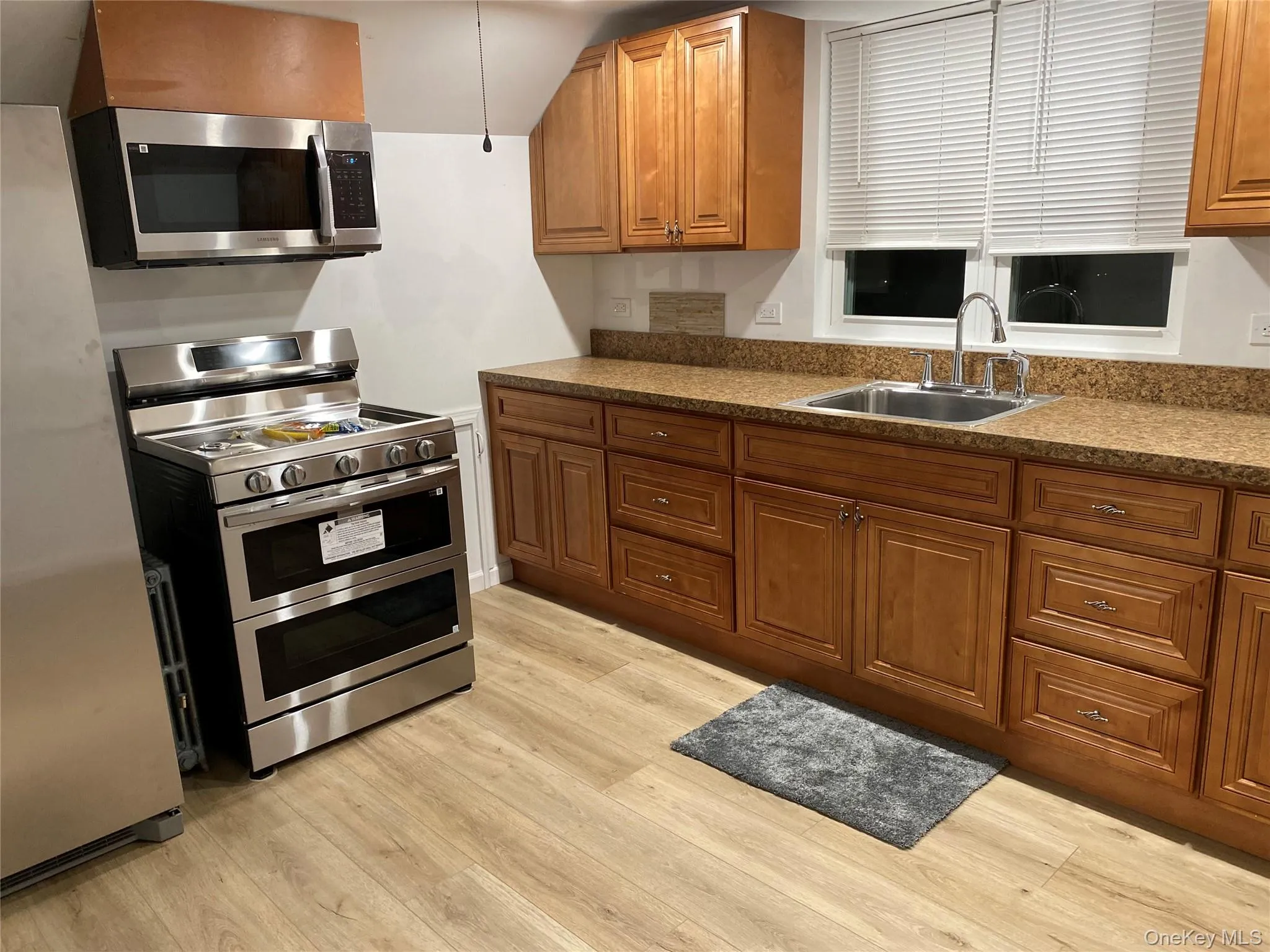 Kitchen with stainless steel appliances, brown cabinets, and light wood-type flooring Kitchen with stainless steel appliances, brown cabinets, and light wood-type flooring