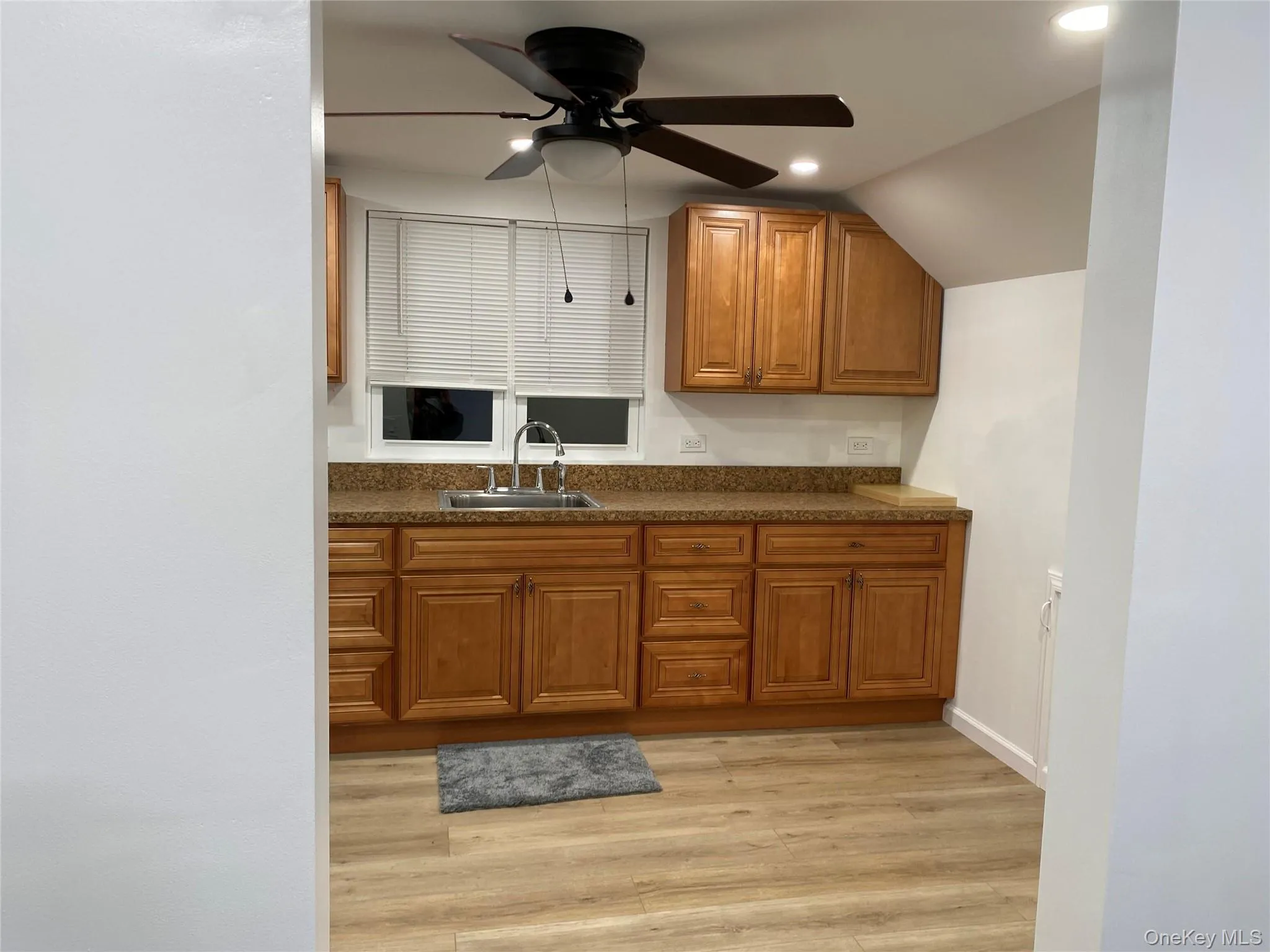 Kitchen with brown cabinets, light wood finished floors, a ceiling fan, and recessed lighting Kitchen with brown cabinets, light wood finished floors, a ceiling fan, and recessed lighting