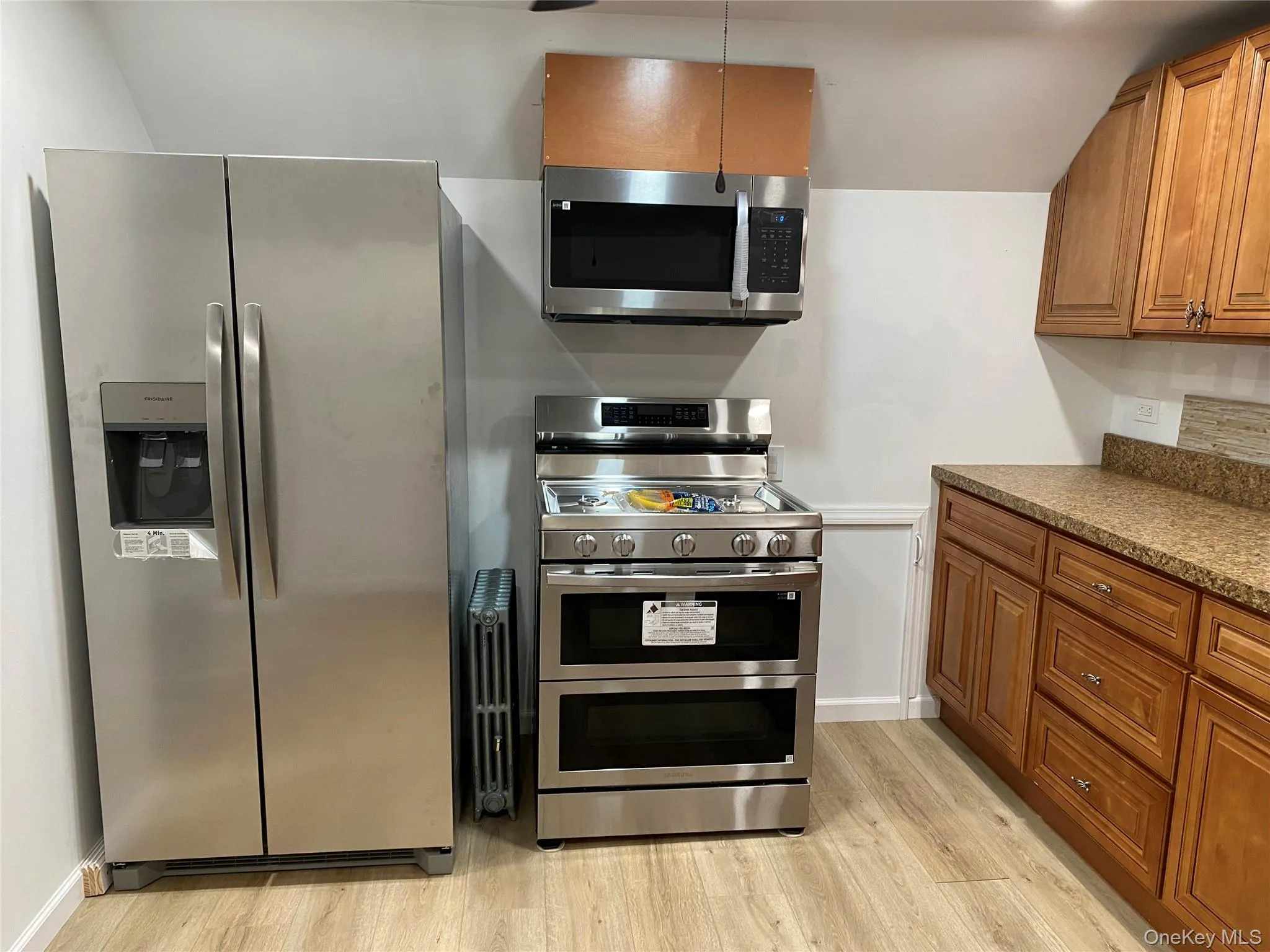 Kitchen with appliances with stainless steel finishes, brown cabinets, and light wood-style flooring Kitchen with appliances with stainless steel finishes, brown cabinets, and light wood-style flooring
