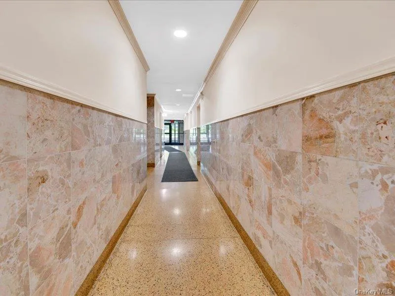 Hall featuring tile walls, speckle patterned floor, recessed lighting, and crown molding Hall featuring tile walls, speckle patterned floor, recessed lighting, and crown molding