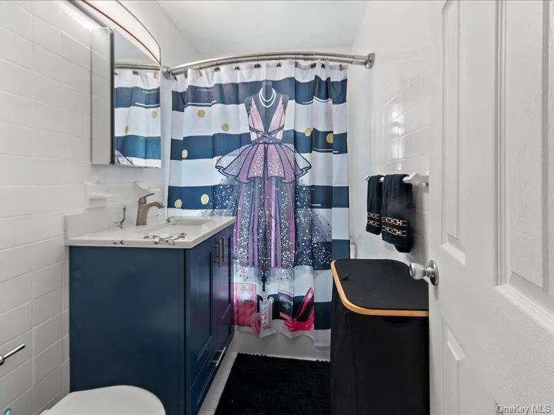 Full bathroom featuring vanity, curtained shower, and tile walls Full bathroom featuring vanity, curtained shower, and tile walls