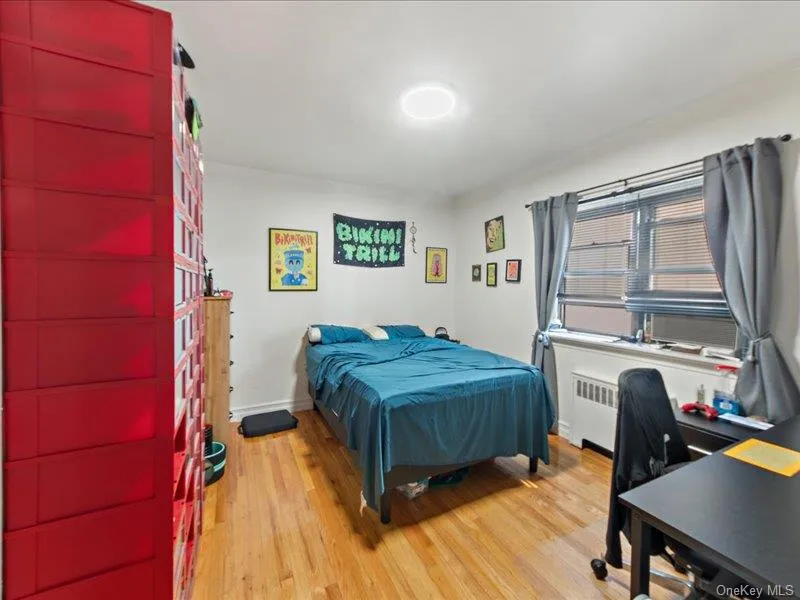 Bedroom with light wood-style flooring and radiator heating unit Bedroom with light wood-style flooring and radiator heating unit