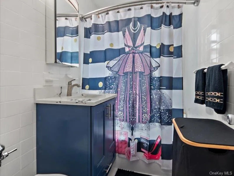Full bath with curtained shower, vanity, and tile walls Full bath with curtained shower, vanity, and tile walls