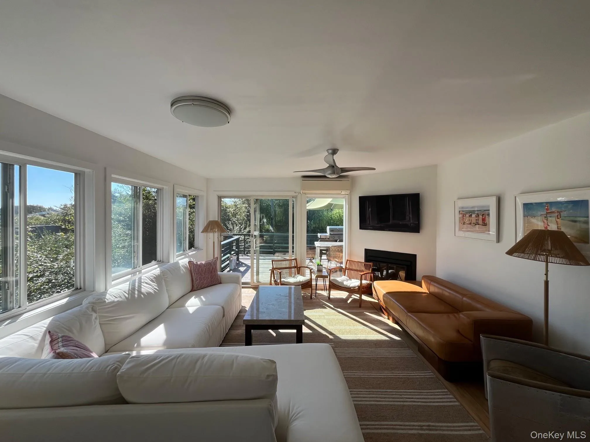 Living room featuring a glass covered fireplace, a ceiling fan, and wood finished floors Living room featuring a glass covered fireplace, a ceiling fan, and wood finished floors