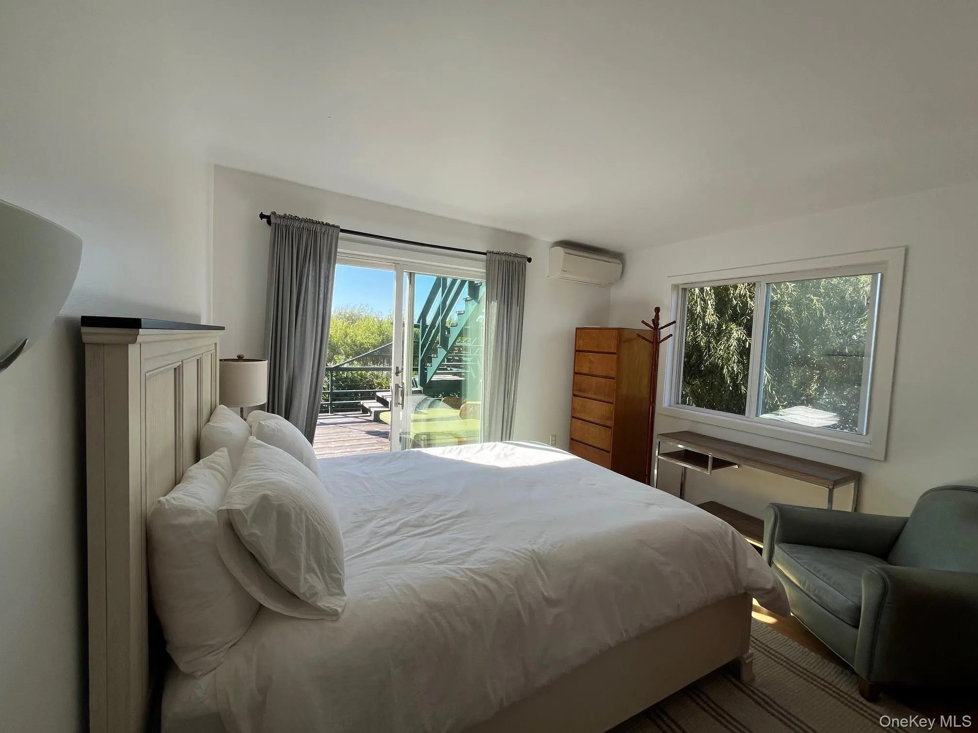 Bedroom featuring multiple windows and a wall mounted air conditioner Bedroom featuring multiple windows and a wall mounted air conditioner