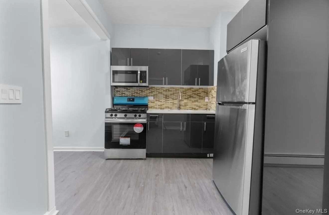Kitchen with stainless steel appliances, tasteful backsplash, a baseboard heating unit, modern cabinets, and light wood finished floors Kitchen with stainless steel appliances, tasteful backsplash, a baseboard heating unit, modern cabinets, and light wood finished floors