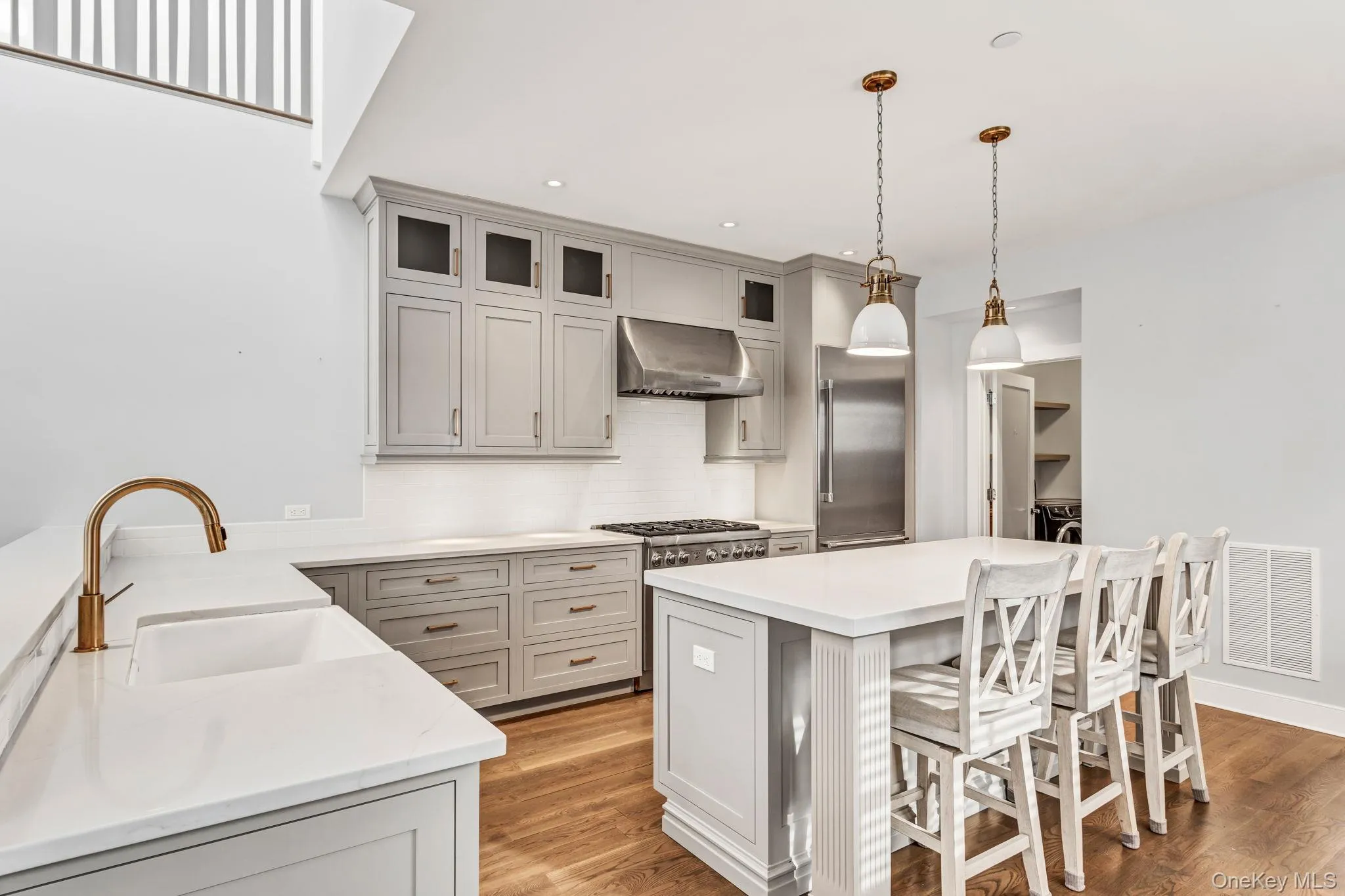 Kitchen with a kitchen bar, tasteful backsplash, hanging light fixtures, a center island, and stainless steel appliances Kitchen with a kitchen bar, tasteful backsplash, hanging light fixtures, a center island, and stainless steel appliances