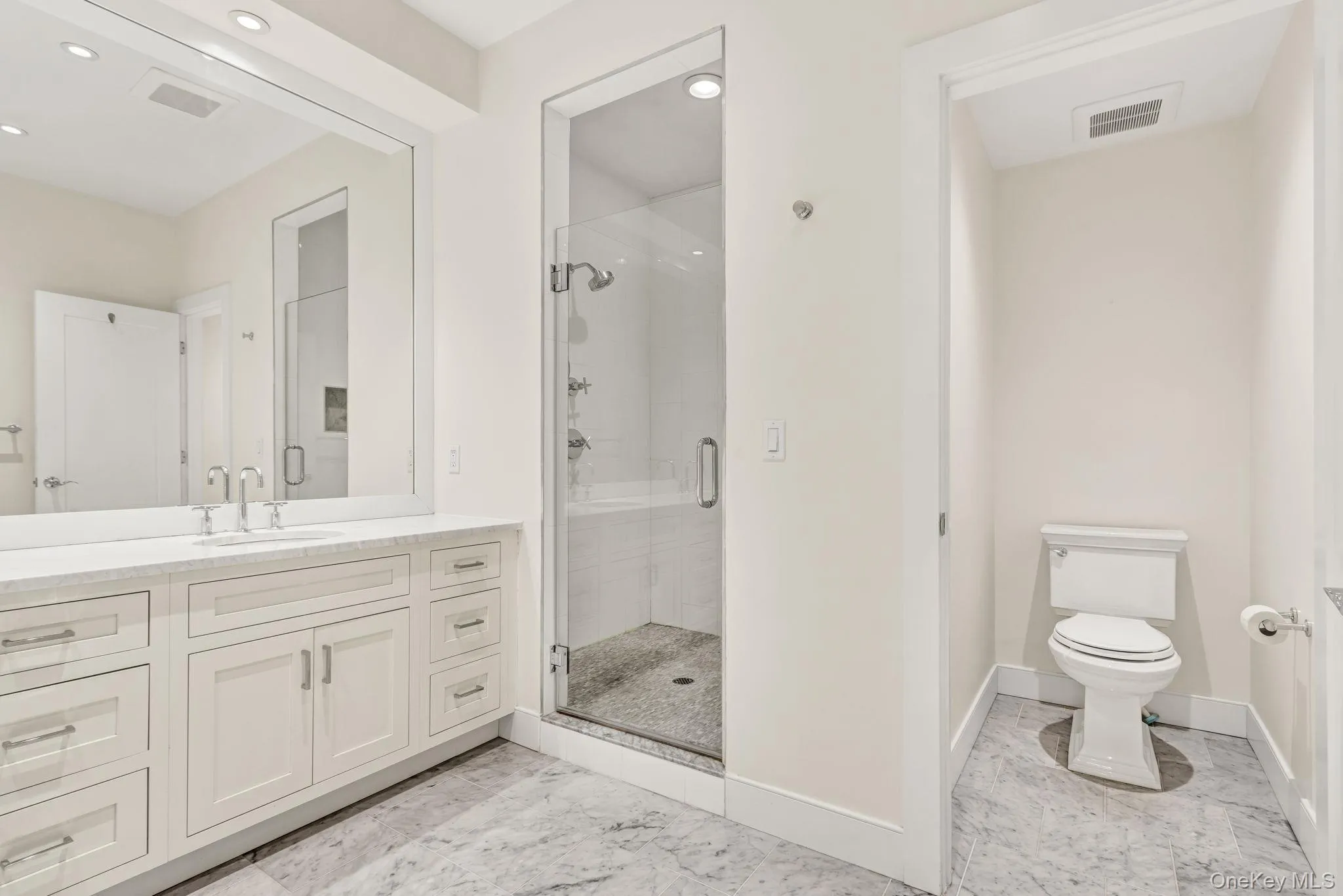 Bathroom featuring a stall shower, vanity, recessed lighting, and light marble finish floors Bathroom featuring a stall shower, vanity, recessed lighting, and light marble finish floors