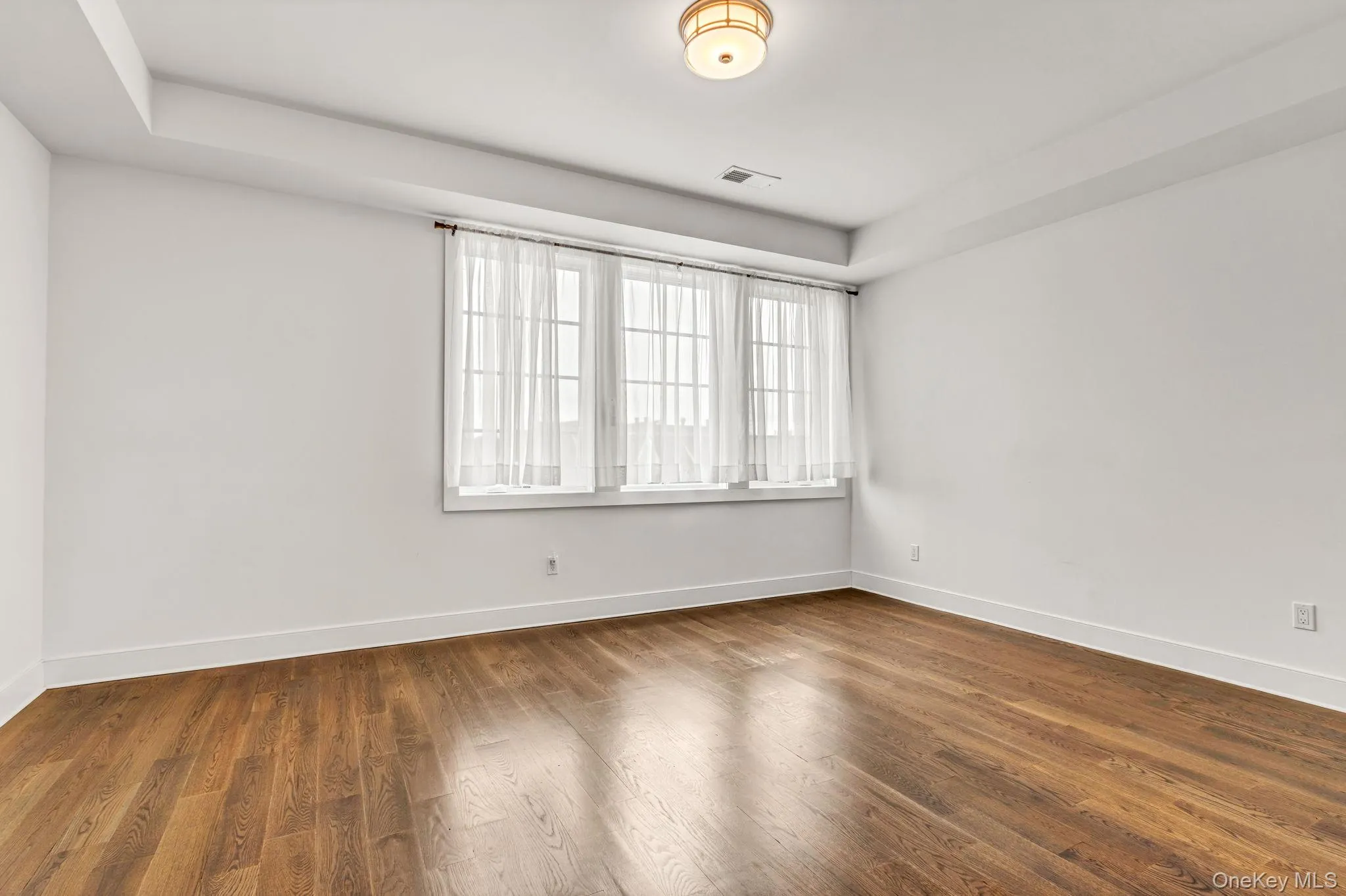 Unfurnished room with wood finished floors and a tray ceiling Unfurnished room with wood finished floors and a tray ceiling