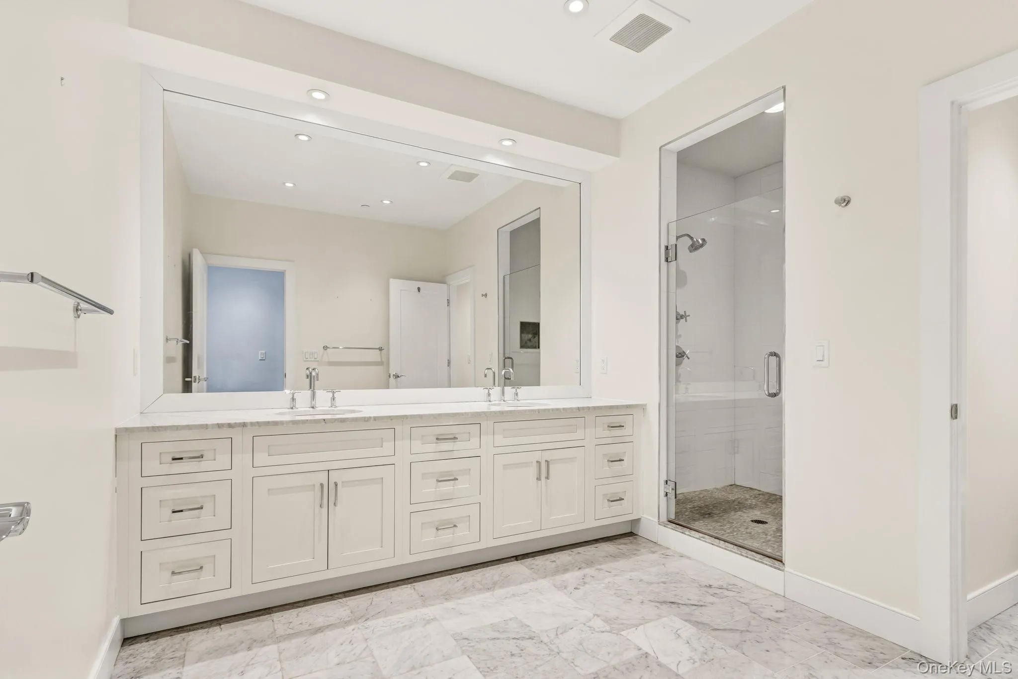 Bathroom featuring double vanity, a stall shower, recessed lighting, and light marble finish floors Bathroom featuring double vanity, a stall shower, recessed lighting, and light marble finish floors