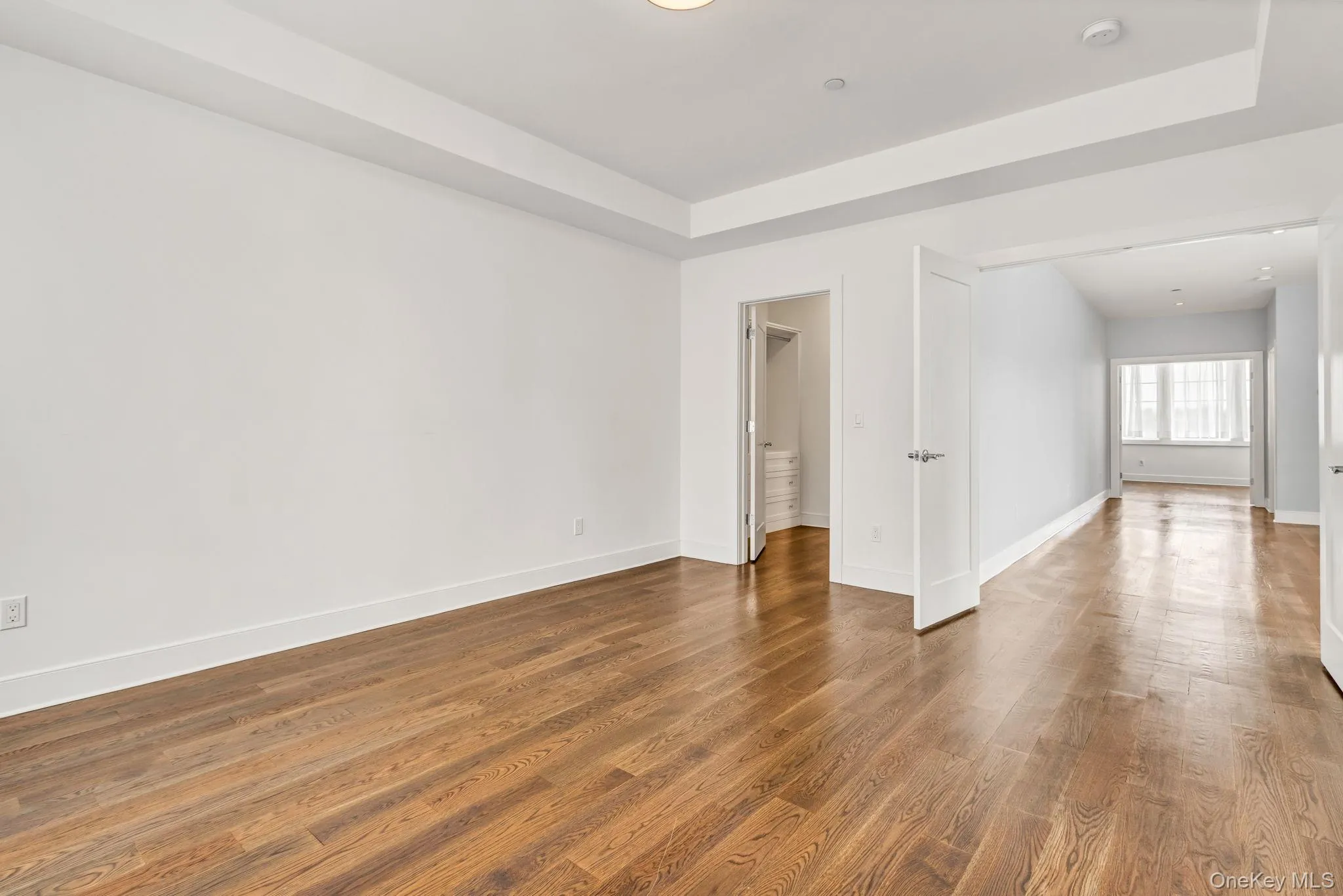 Empty room with wood finished floors and a tray ceiling Empty room with wood finished floors and a tray ceiling