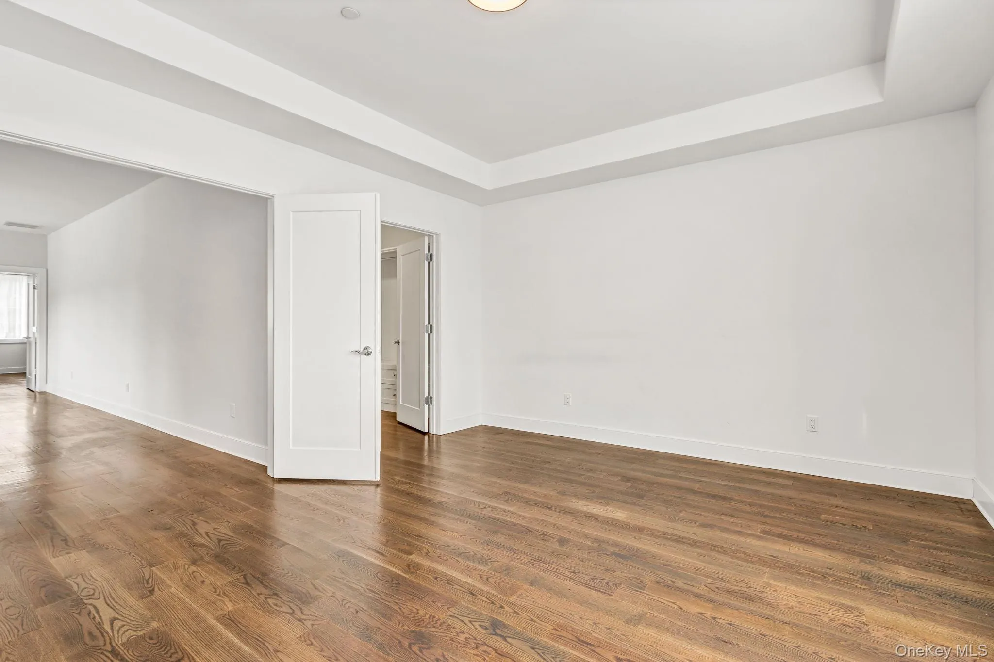 Empty room featuring dark wood-style flooring and a tray ceiling Empty room featuring dark wood-style flooring and a tray ceiling