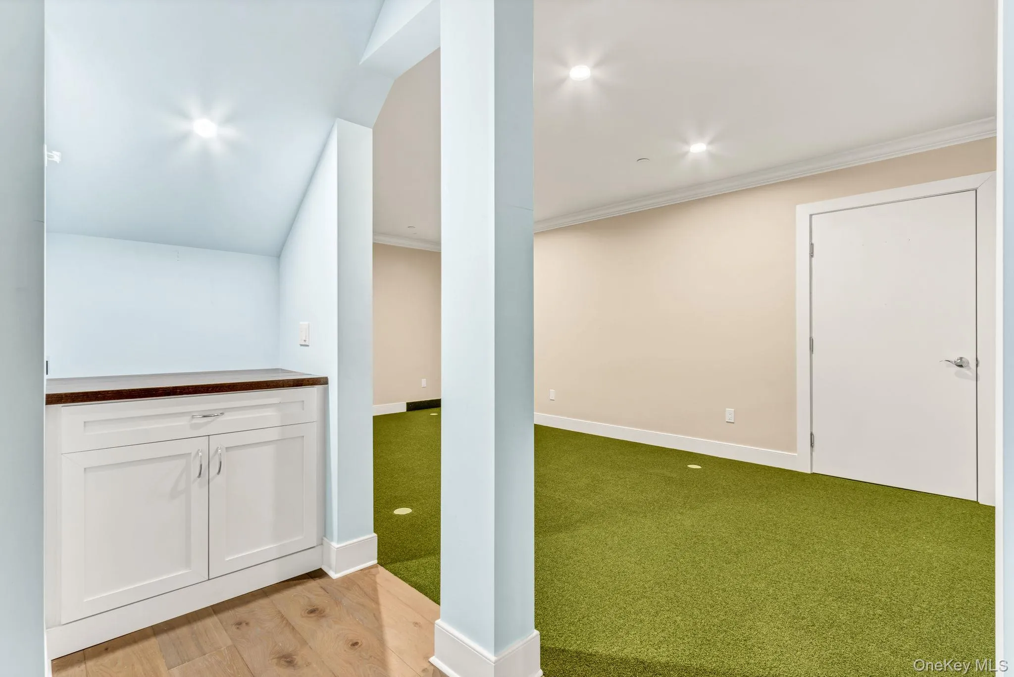 Basement with a putting green, crown molding, light wood finished floors, recessed lighting, and light colored carpet Basement with a putting green, crown molding, light wood finished floors, recessed lighting, and light colored carpet
