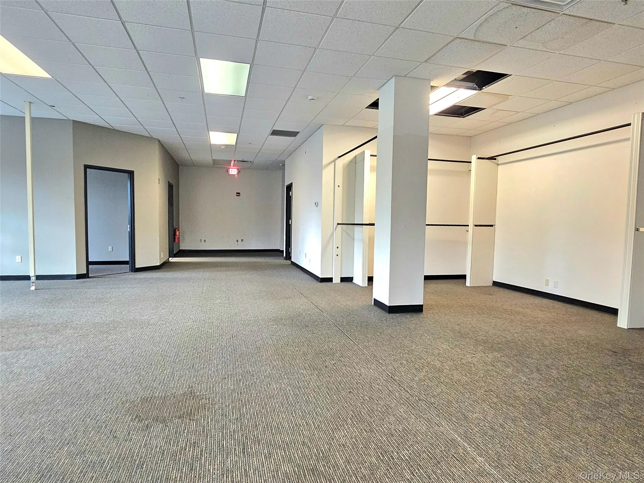 Empty room featuring a drop ceiling and light colored carpet Empty room featuring a drop ceiling and light colored carpet