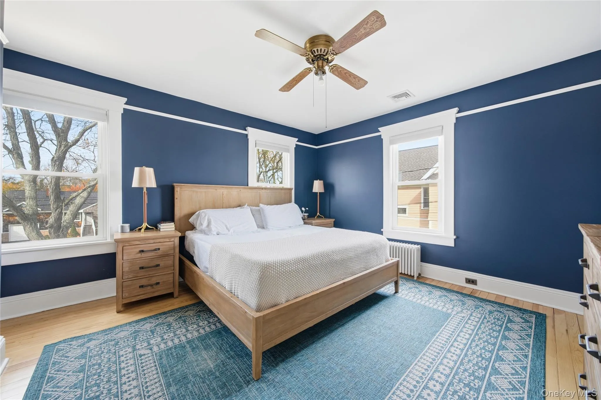 Bedroom with light wood finished floors, radiator, and ceiling fan Bedroom with light wood finished floors, radiator, and ceiling fan