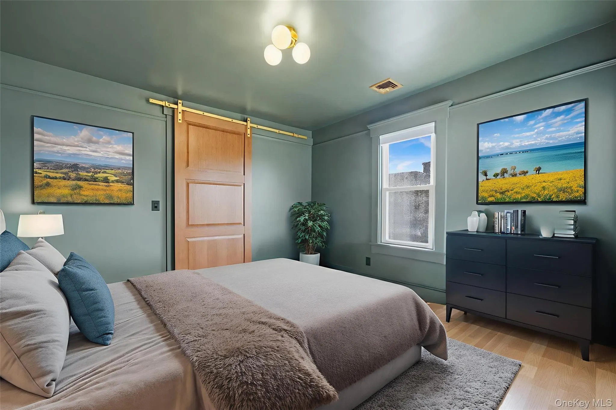 Bedroom featuring a barn door and light wood-style floors Bedroom featuring a barn door and light wood-style floors