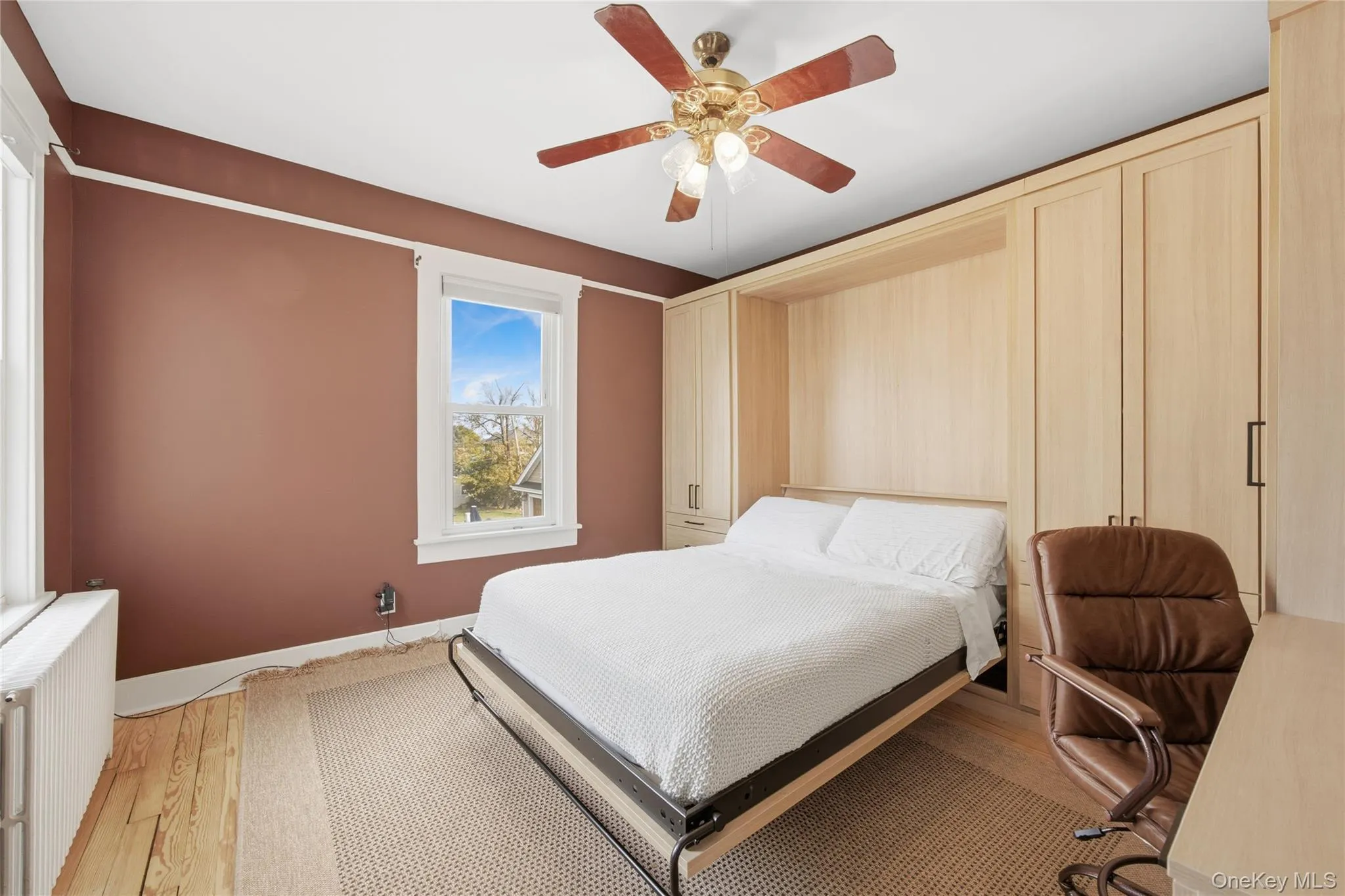 Bedroom featuring radiator heating unit, light wood-style floors, and a ceiling fan Bedroom featuring radiator heating unit, light wood-style floors, and a ceiling fan