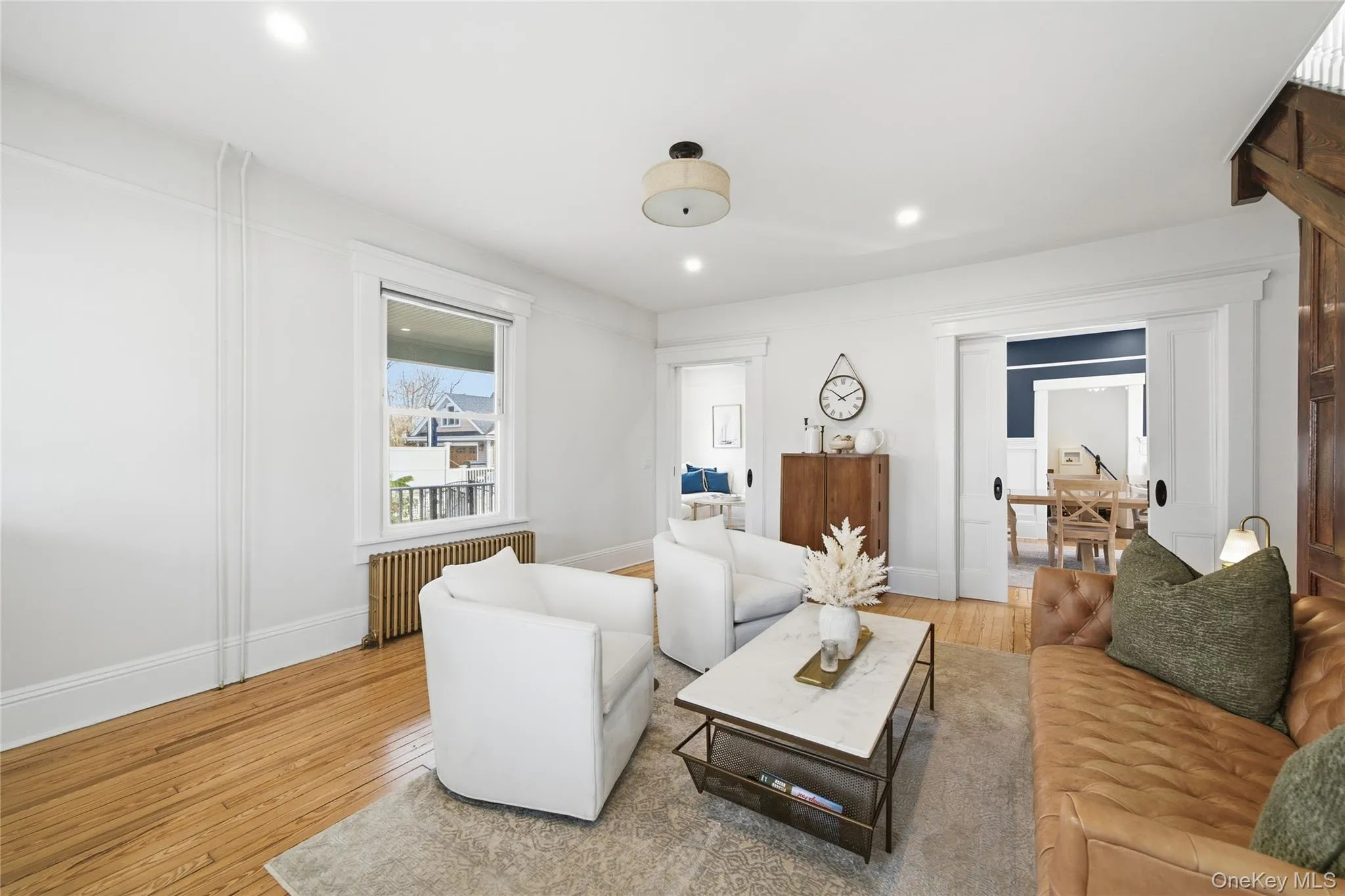 Living area with light wood-style flooring, radiator heating unit, and recessed lighting Living area with light wood-style flooring, radiator heating unit, and recessed lighting