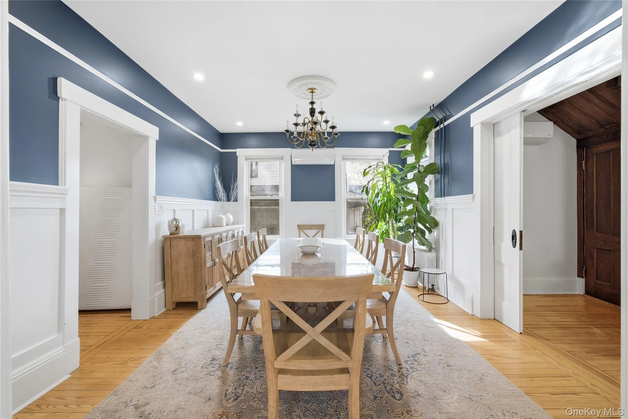 Dining room with light wood-type flooring, a chandelier, a decorative wall, recessed lighting, and wainscoting Dining room with light wood-type flooring, a chandelier, a decorative wall, recessed lighting, and wainscoting
