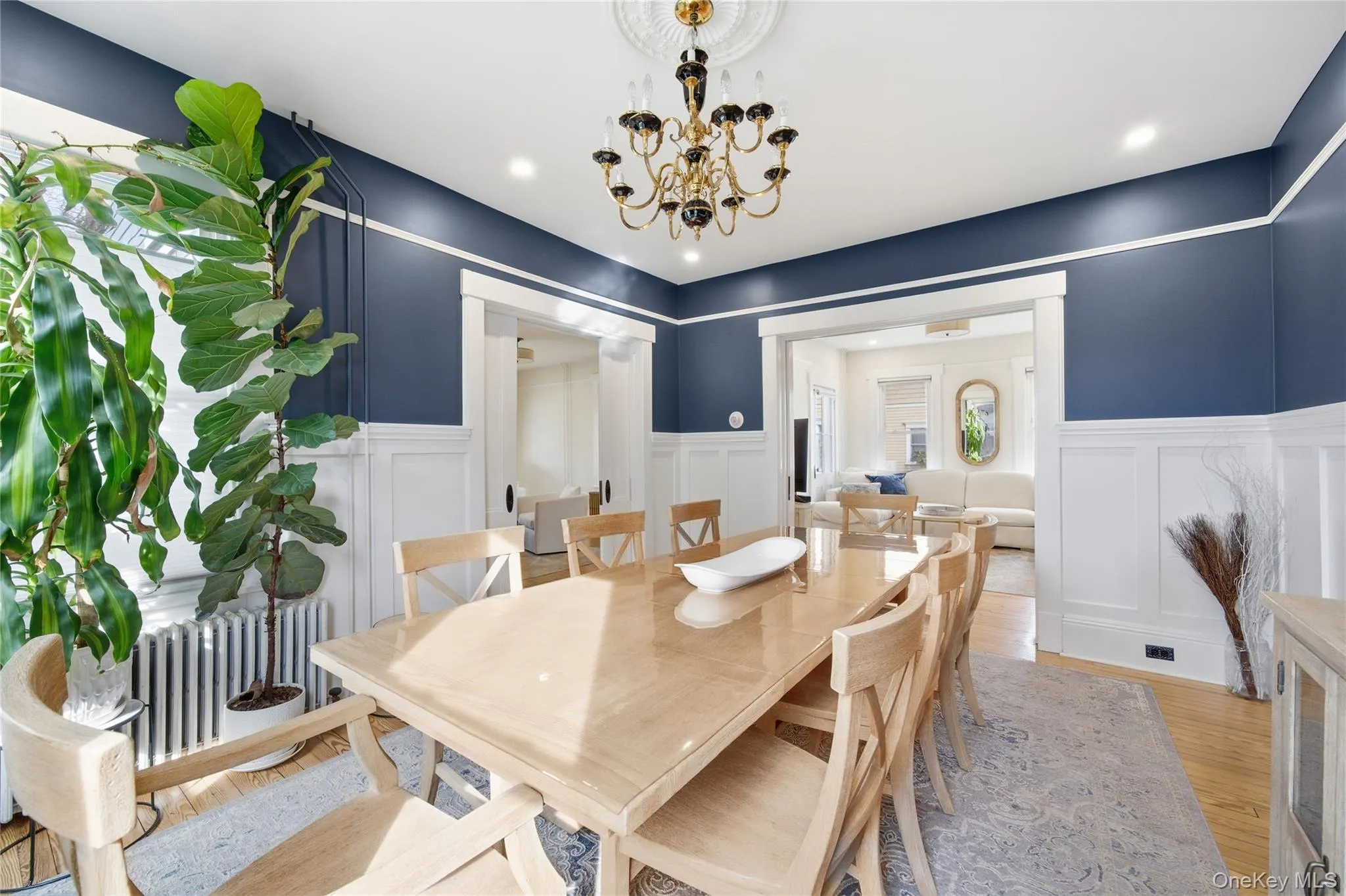 Dining space featuring a decorative wall, wood finished floors, radiator heating unit, a chandelier, and wainscoting Dining space featuring a decorative wall, wood finished floors, radiator heating unit, a chandelier, and wainscoting