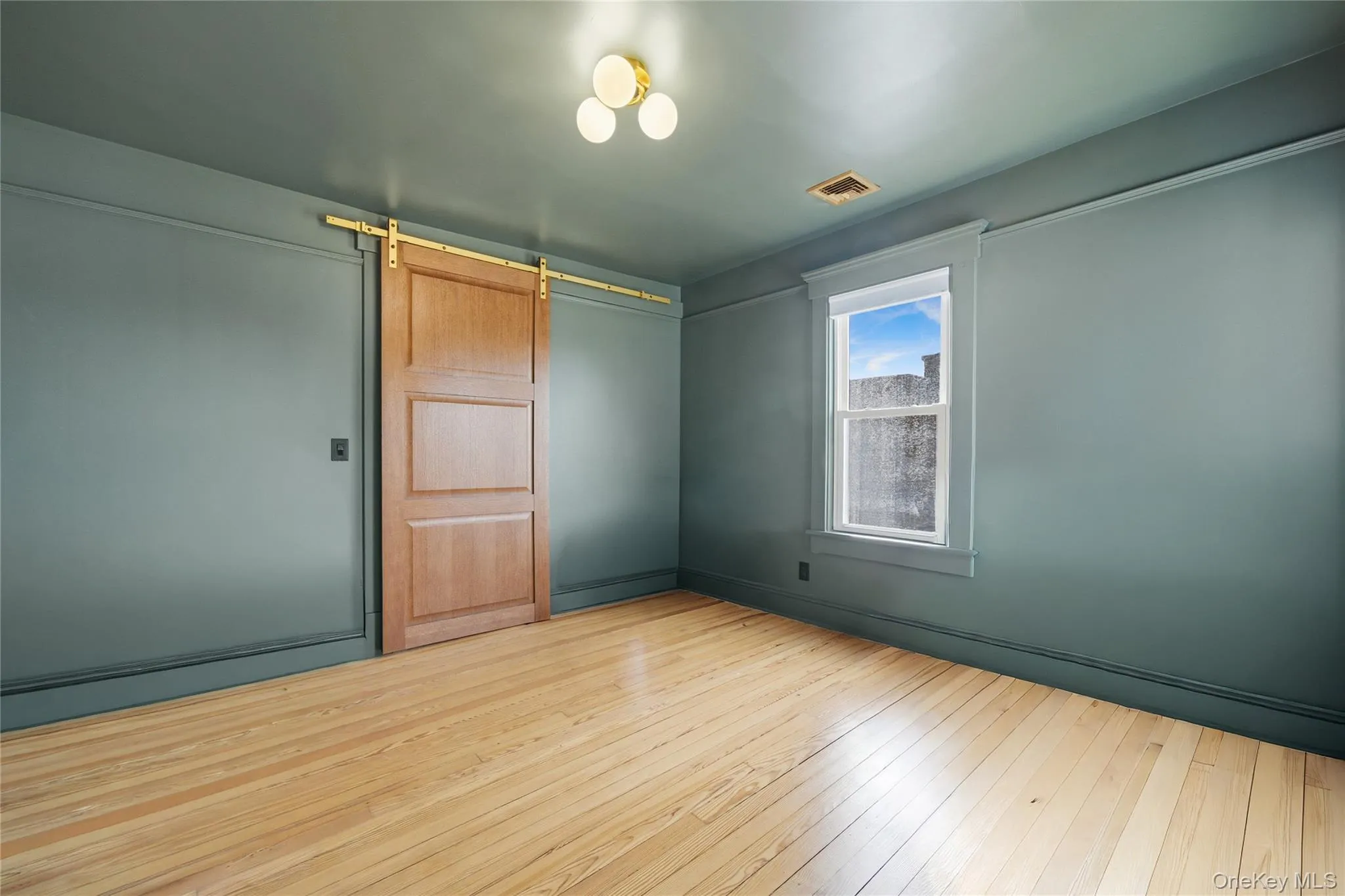 Spare room featuring a barn door and hardwood / wood-style flooring Spare room featuring a barn door and hardwood / wood-style flooring