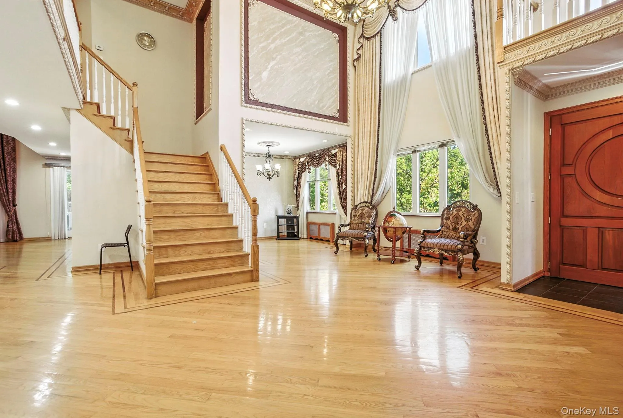 Entrance foyer with a chandelier, a high ceiling, wood finished floors, and stairs Entrance foyer with a chandelier, a high ceiling, wood finished floors, and stairs