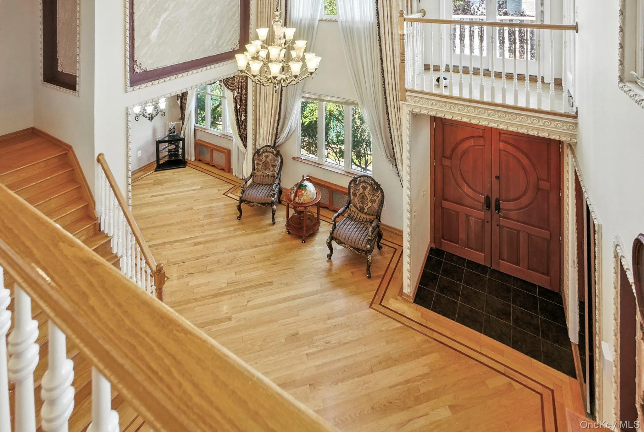 Entrance foyer with light wood-style floors, a chandelier, and a towering ceiling Entrance foyer with light wood-style floors, a chandelier, and a towering ceiling