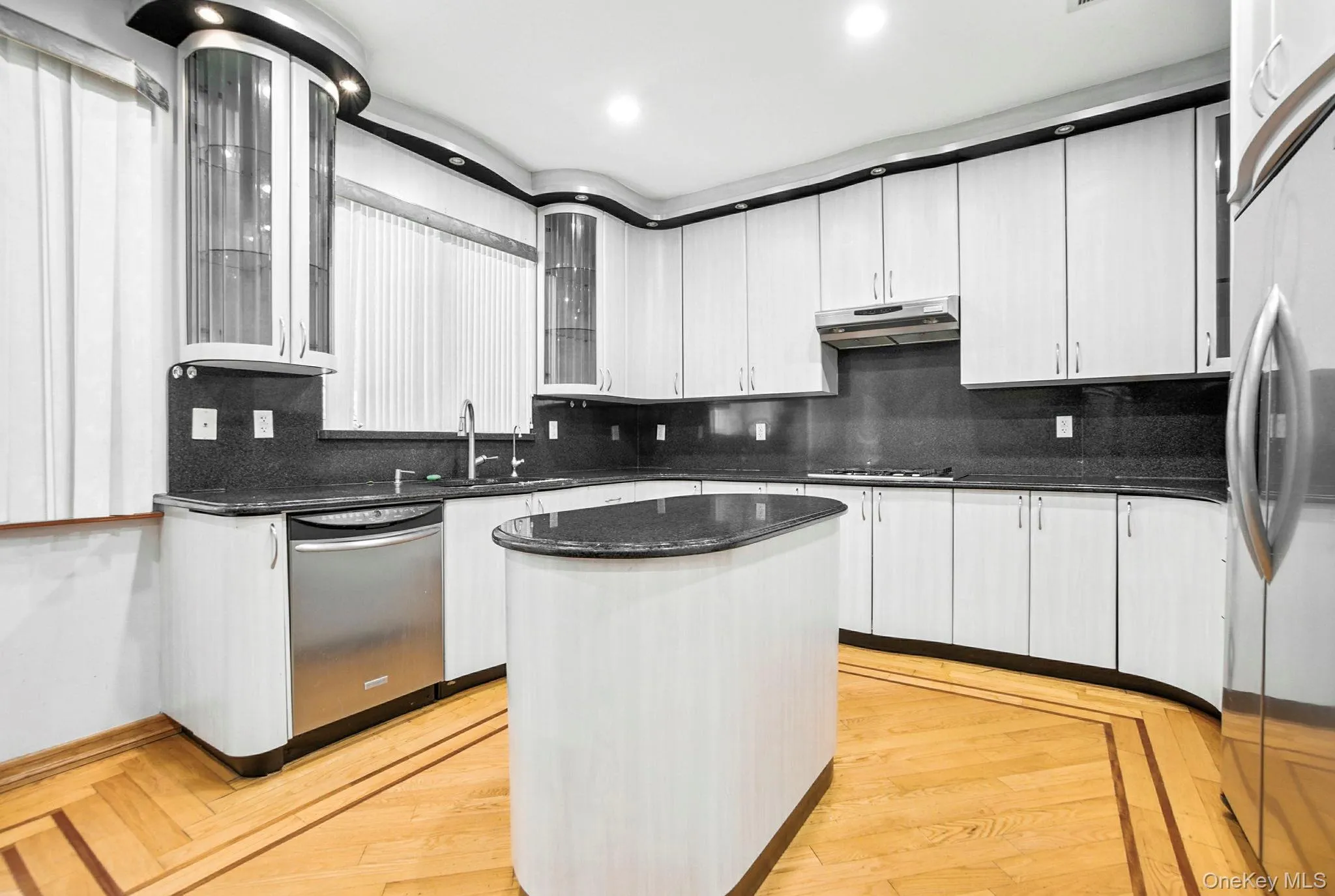 Kitchen with backsplash, dark stone counters, a center island, stainless steel appliances, and recessed lighting Kitchen with backsplash, dark stone counters, a center island, stainless steel appliances, and recessed lighting