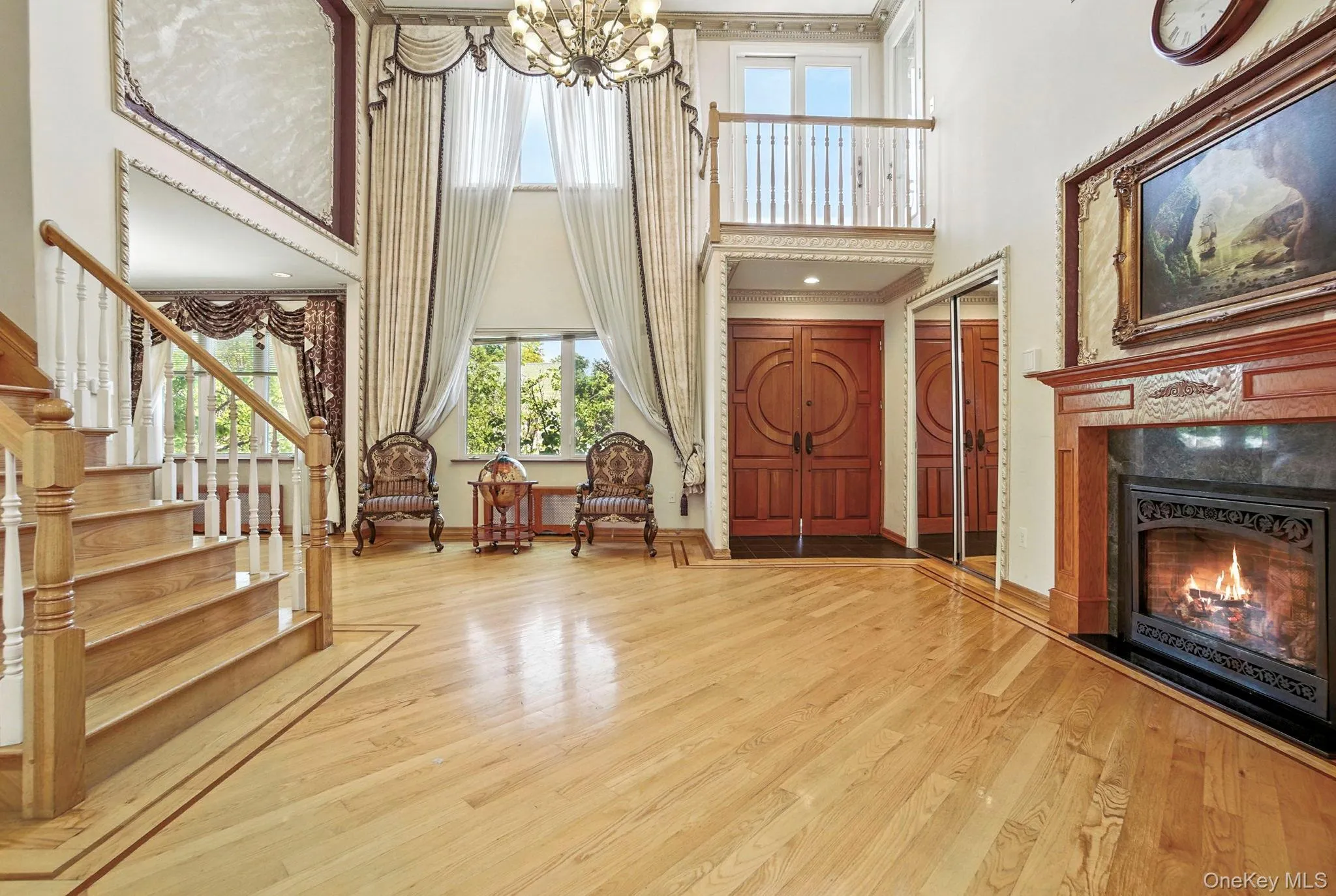 Entrance foyer featuring a towering ceiling, wood finished floors, stairway, a tiled fireplace, and a chandelier Entrance foyer featuring a towering ceiling, wood finished floors, stairway, a tiled fireplace, and a chandelier