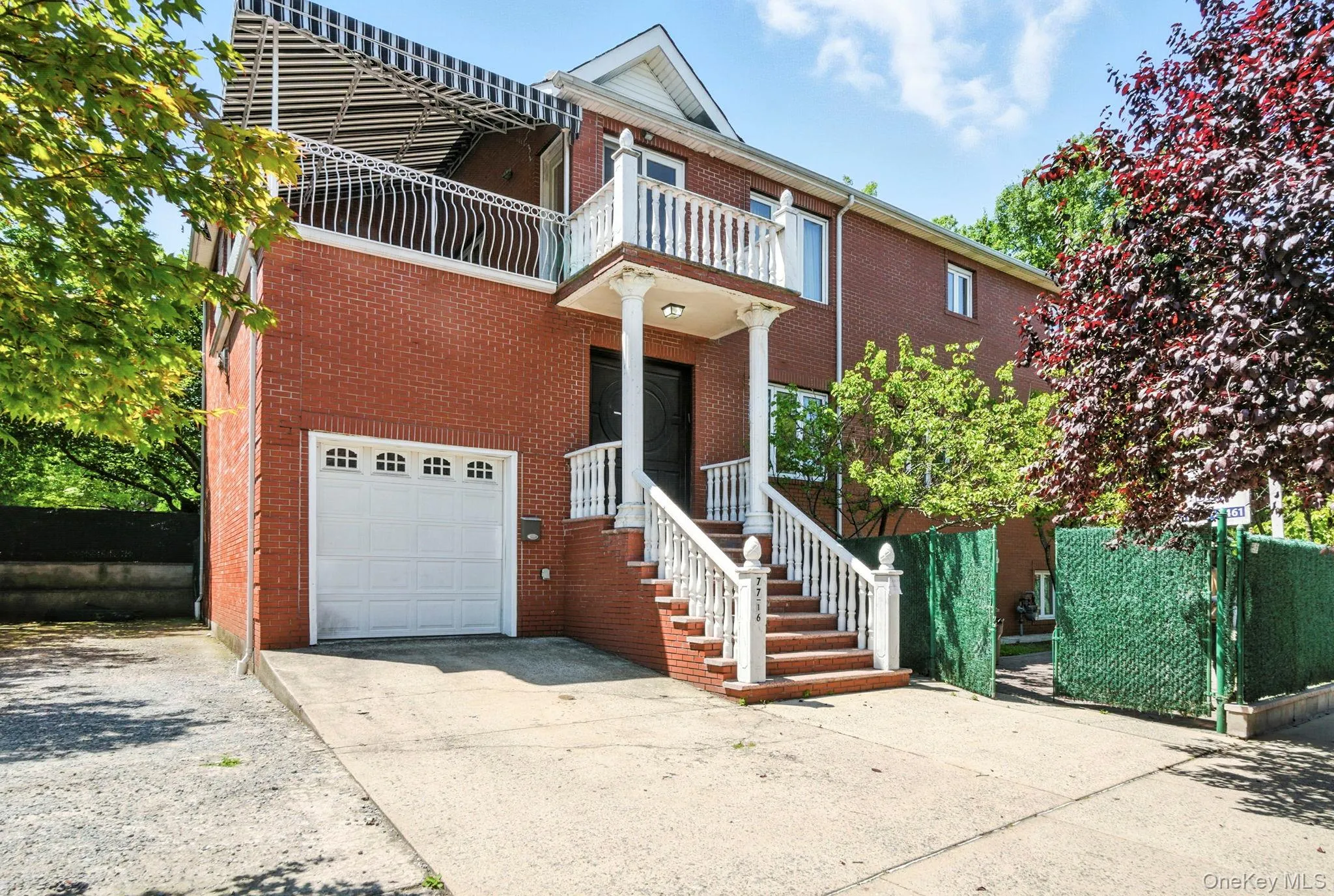 View of front facade with driveway, an attached garage, brick siding, and a balcony View of front facade with driveway, an attached garage, brick siding, and a balcony