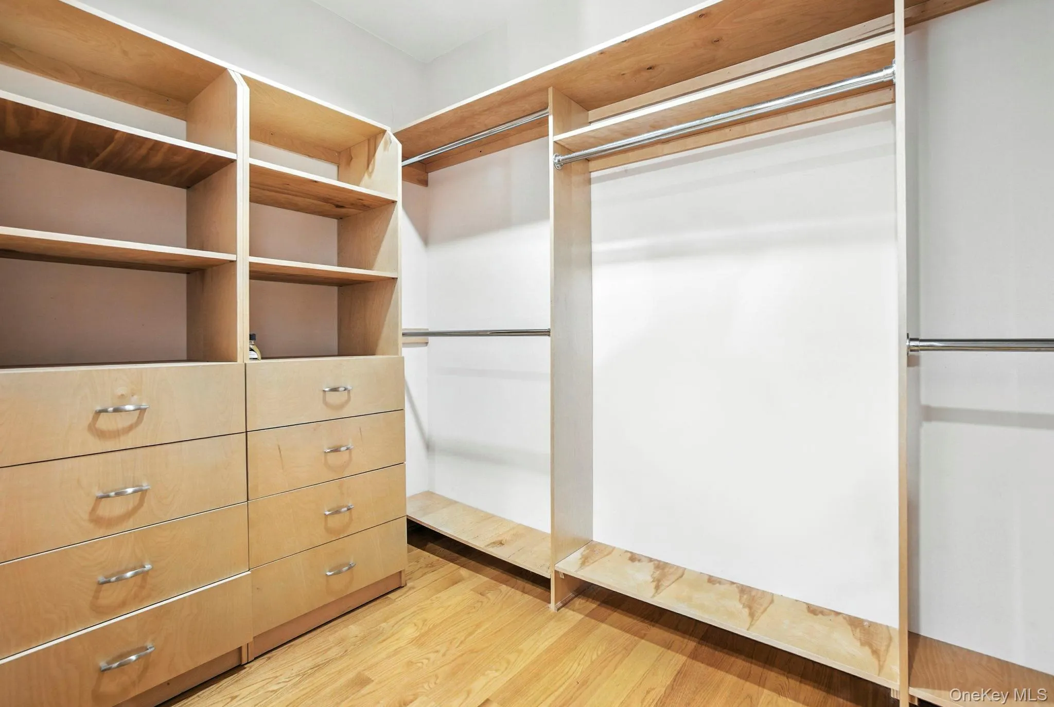 Walk in closet with light wood-style flooring Walk in closet with light wood-style flooring