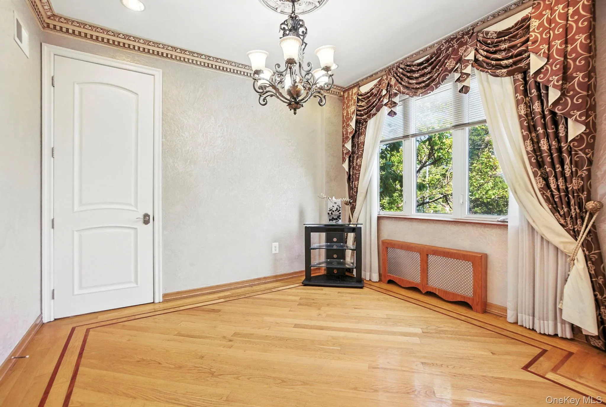 Unfurnished dining area with radiator heating unit, wood finished floors, a chandelier, and a textured wall Unfurnished dining area with radiator heating unit, wood finished floors, a chandelier, and a textured wall