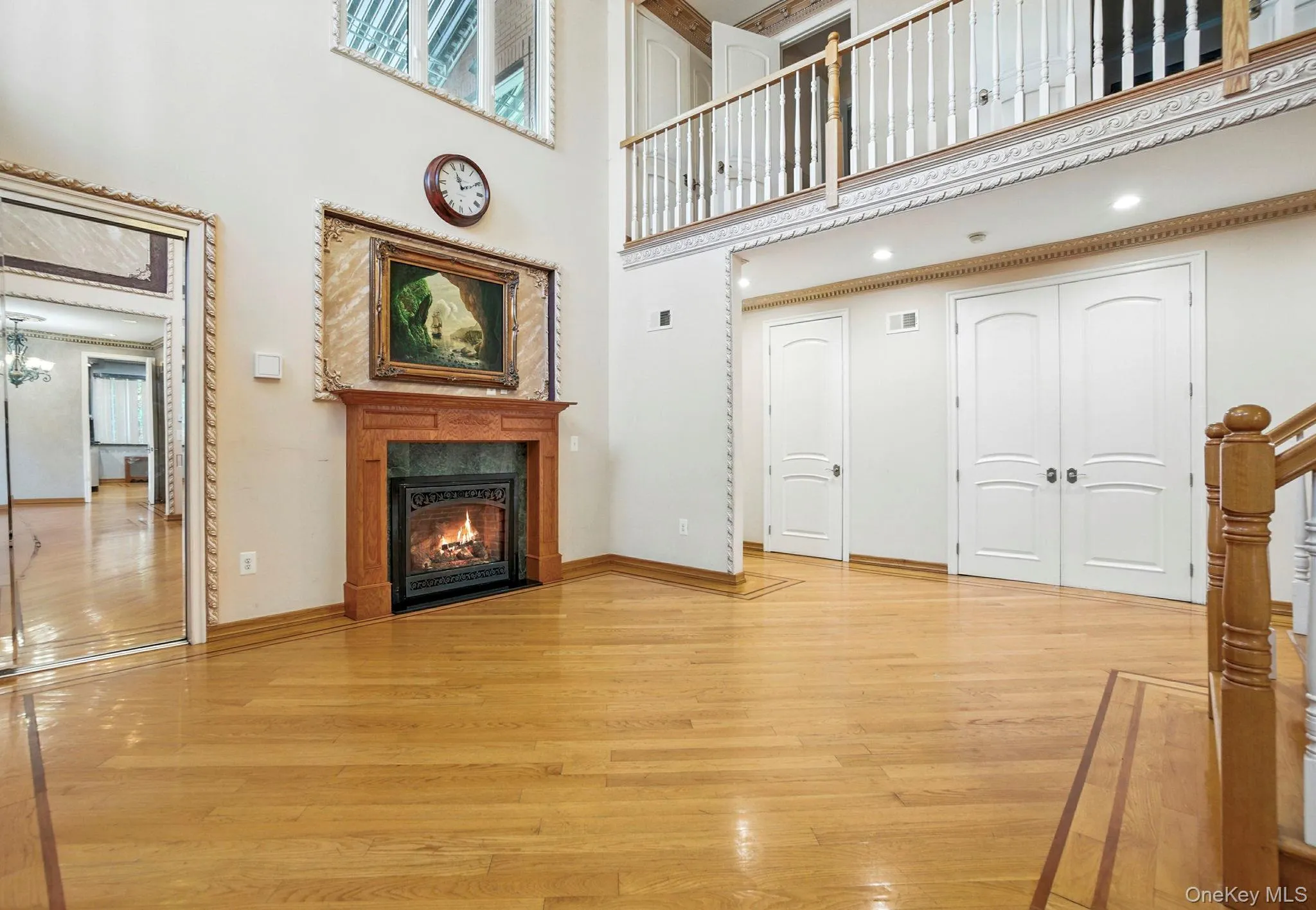 Unfurnished living room with light wood finished floors, a fireplace with flush hearth, and a towering ceiling Unfurnished living room with light wood finished floors, a fireplace with flush hearth, and a towering ceiling