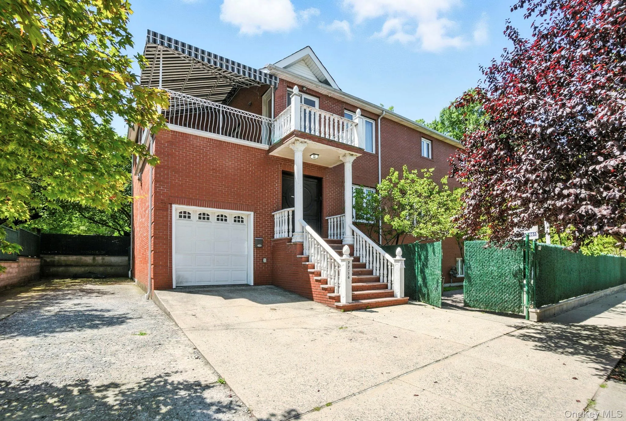 View of front of home with driveway, brick siding, an attached garage, and a balcony View of front of home with driveway, brick siding, an attached garage, and a balcony